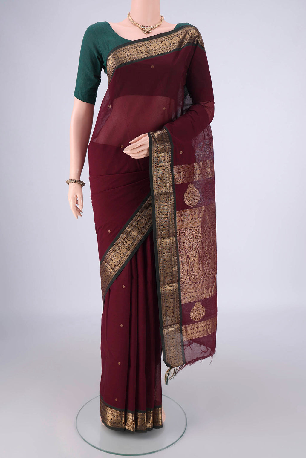 Maroon Kanchi Cotton Saree with Zari Butta on the body and Zari Border.  displayed on a mannequin