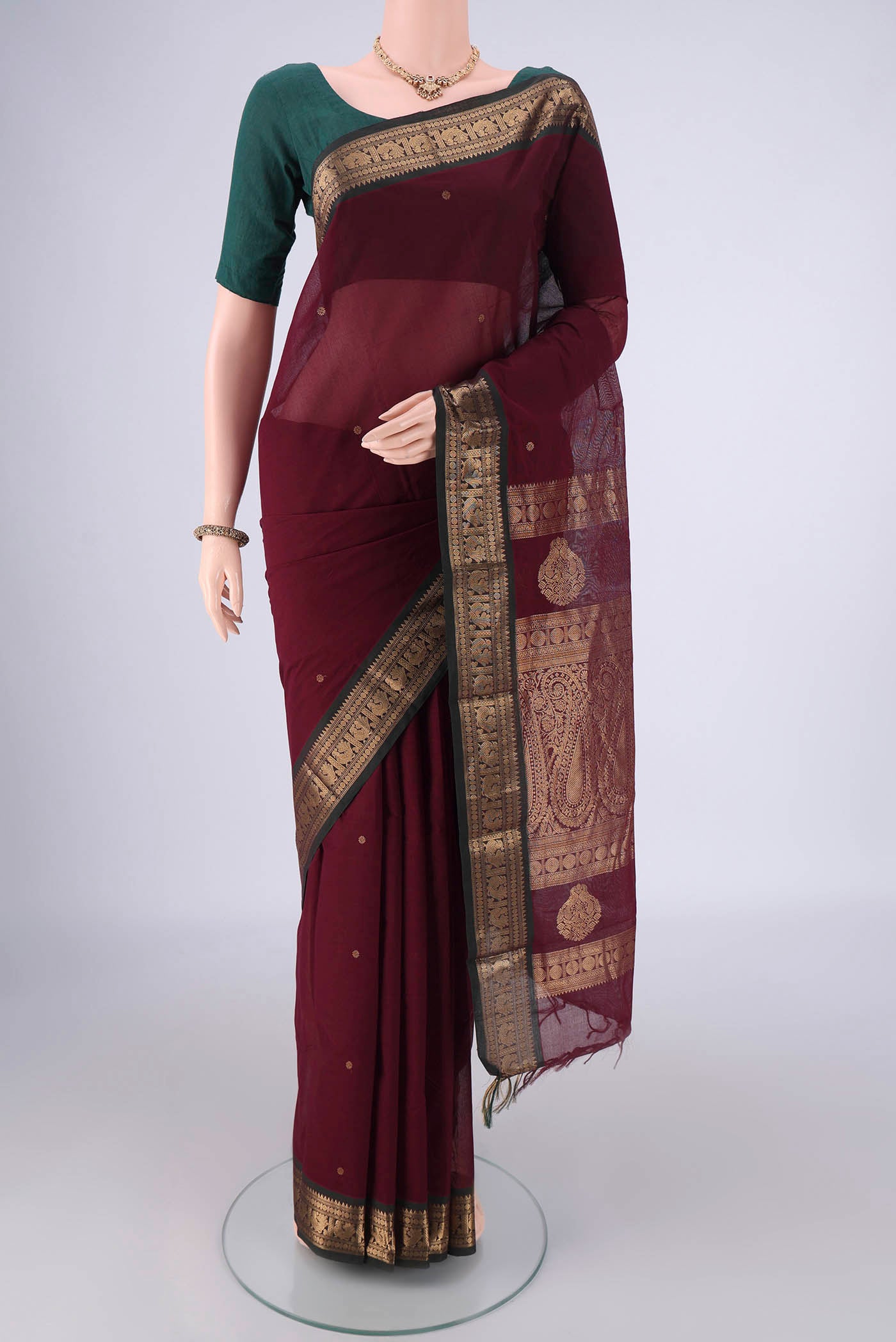 Maroon Kanchi Cotton Saree with Zari Butta on the body and Zari Border.  displayed on a mannequin