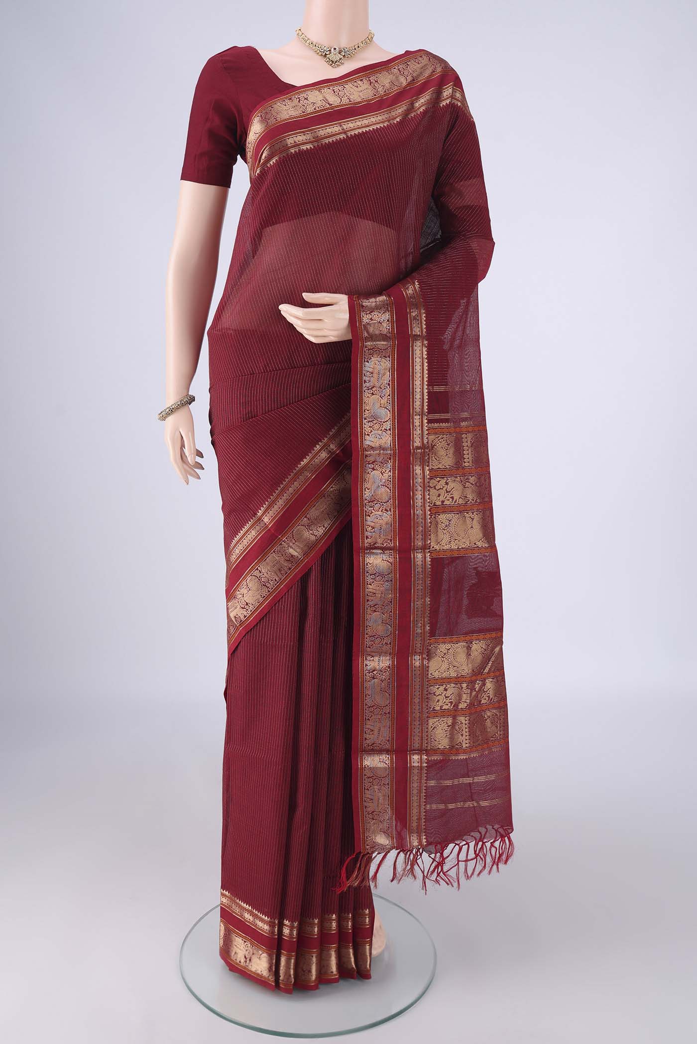Maroon Kanchi Cotton Saree with Stripes on the body and Zari Border.  displayed on a mannequin