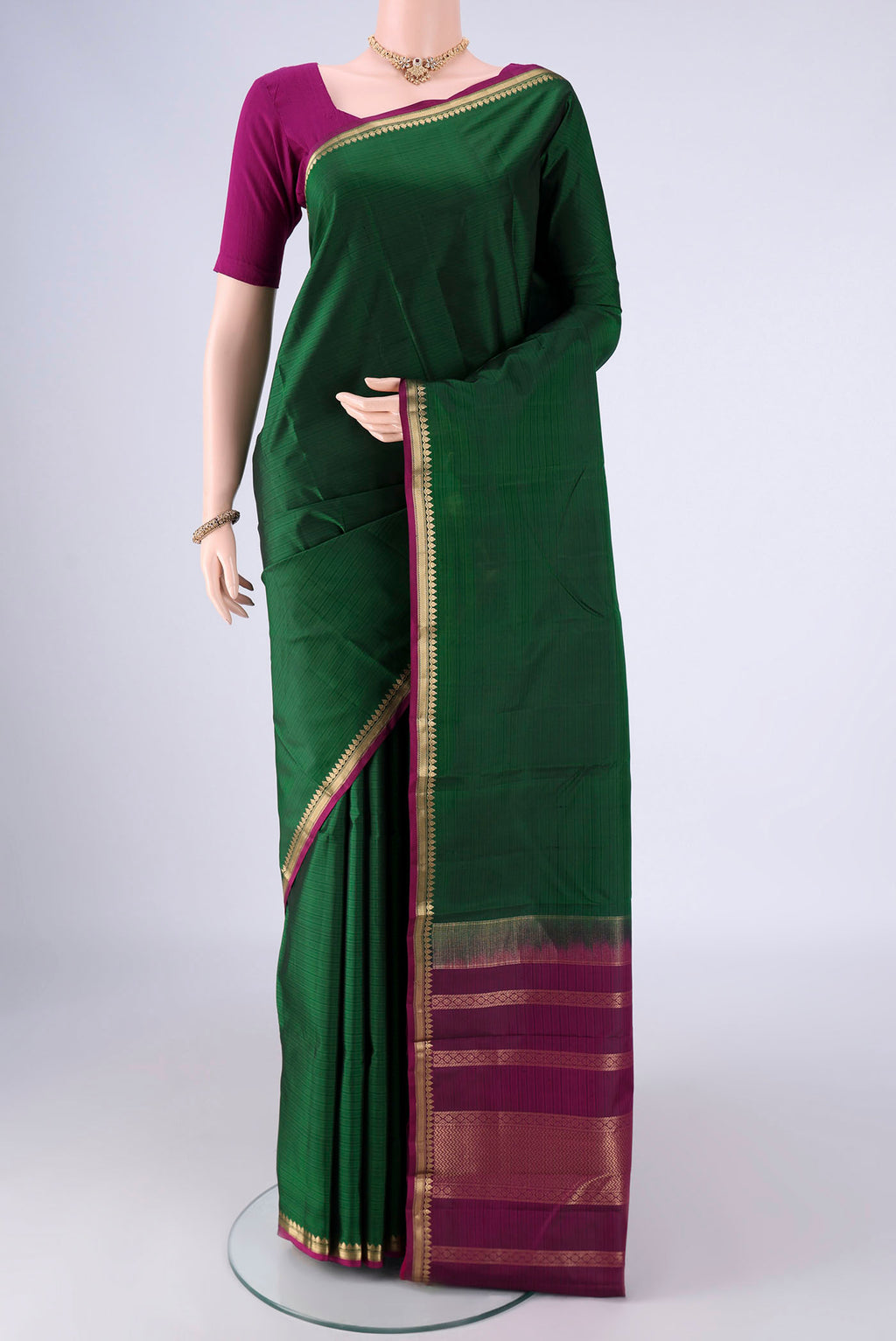 Bottle Green Kanjivaram Silk Saree with Plain Body and Zari Border.  displayed on a mannequin
