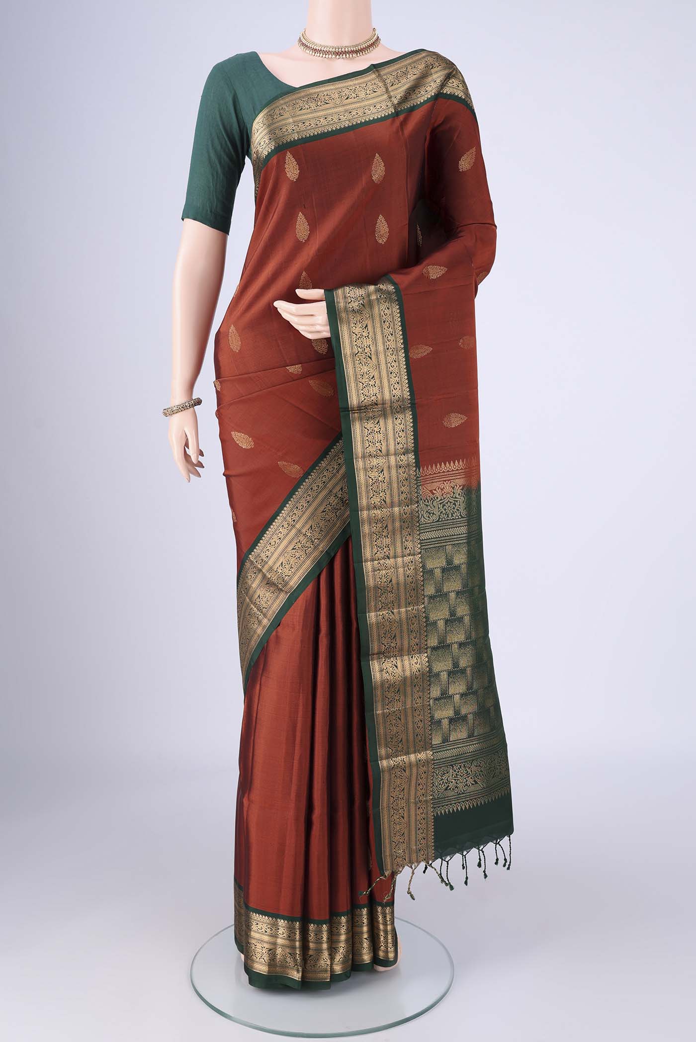 Rust Soft Silk Saree with Zari Butta on the body and Zari Border.  displayed on a mannequin