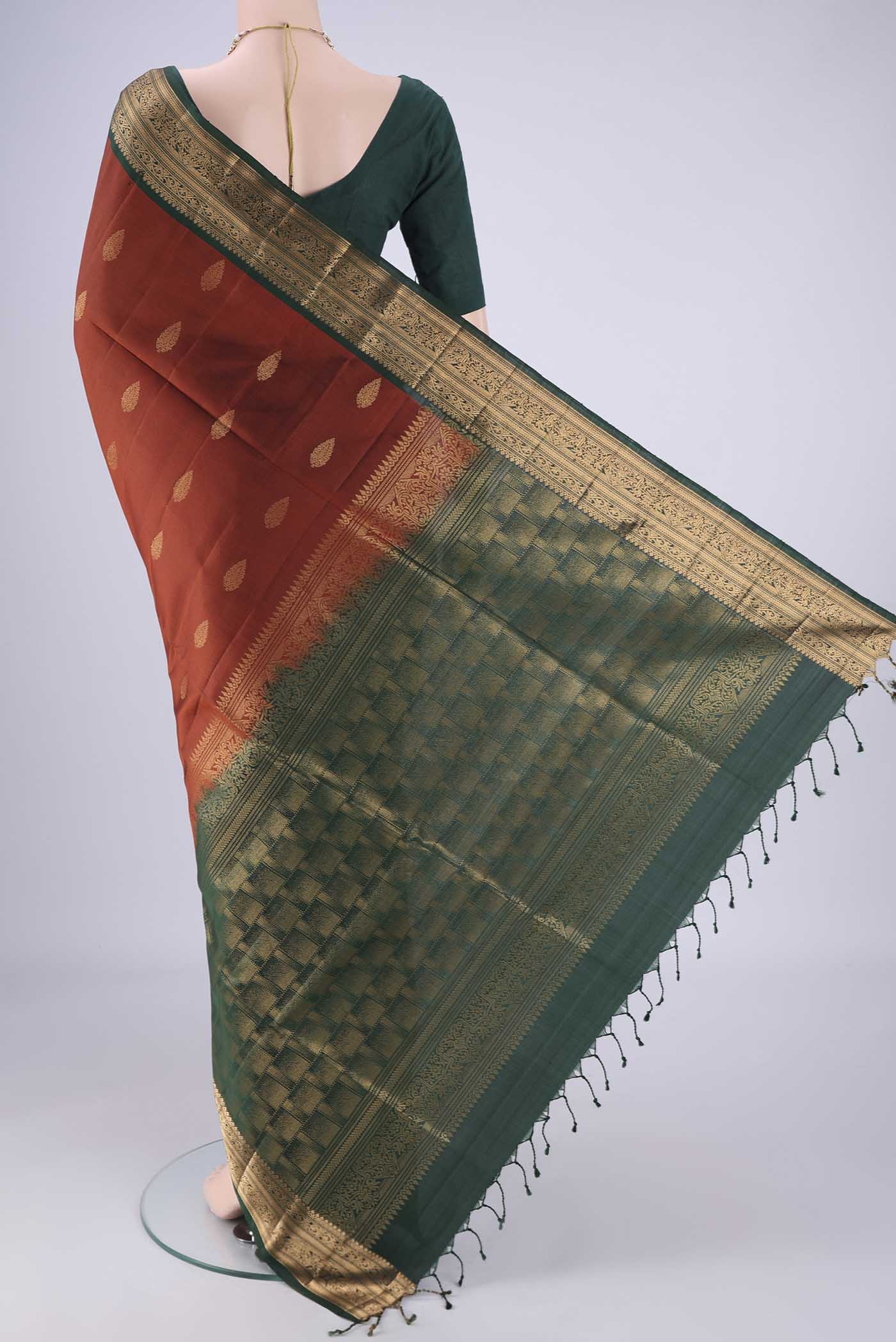 Flat view of Rust Soft Silk Saree with Zari Butta on the body and Zari Border. 