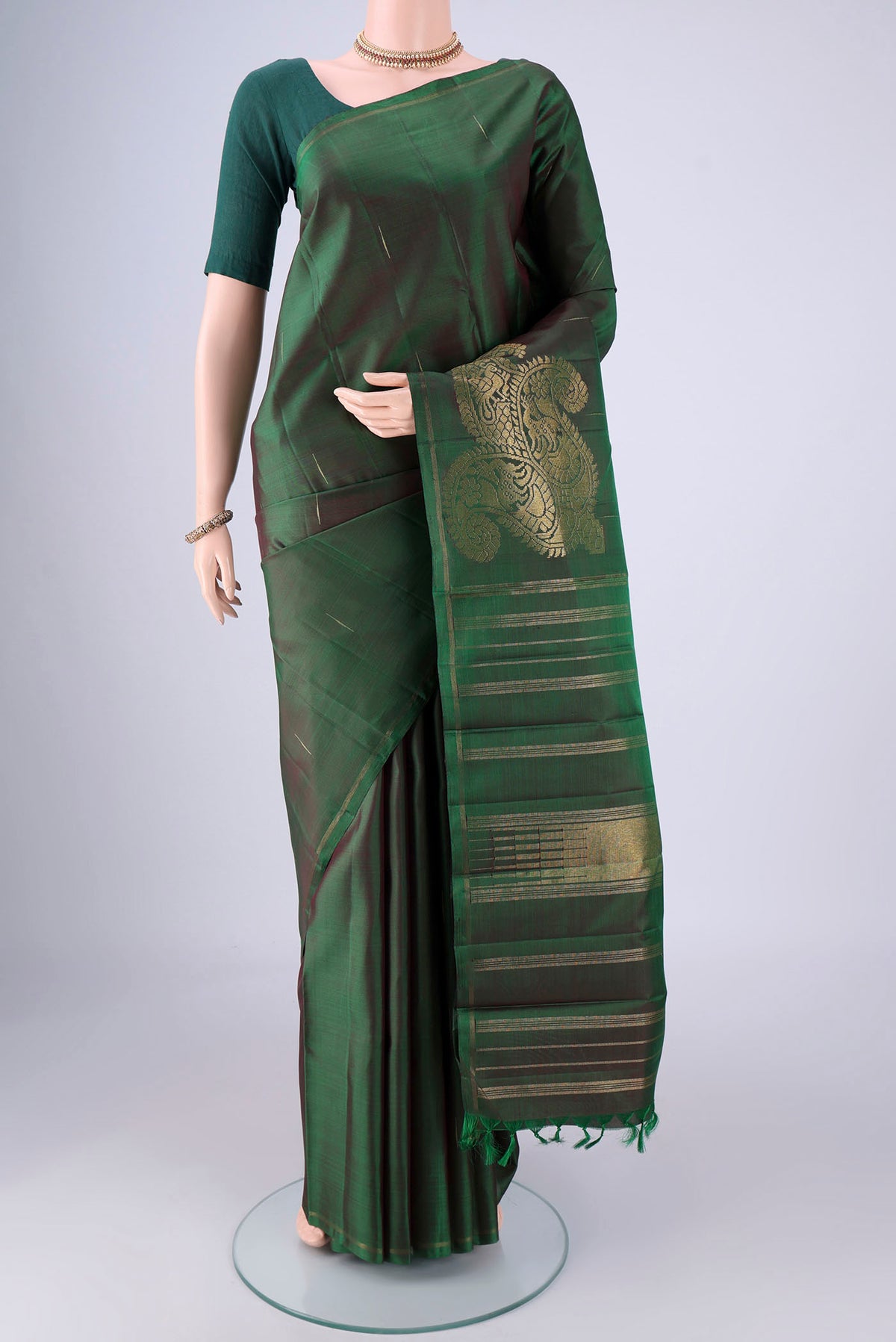 Bottle Green Kanjivaram Silk Saree with Zari Butta on the body and Plain Border.  displayed on a mannequin