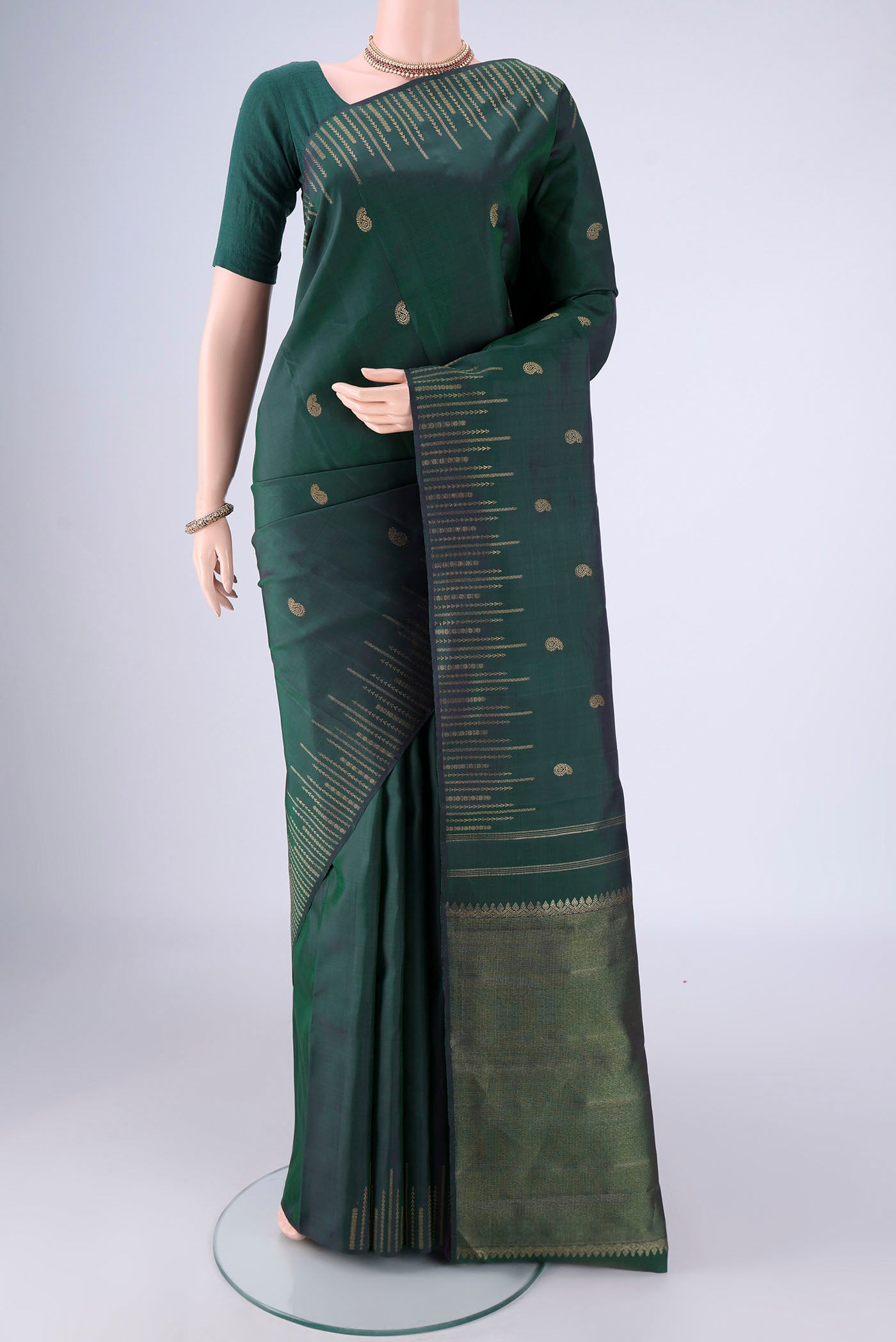 Pure Silk Pure Zari Bottle Green Kanchipuram Saree with Zari Butta on the body and Zari Border.  displayed on a mannequin