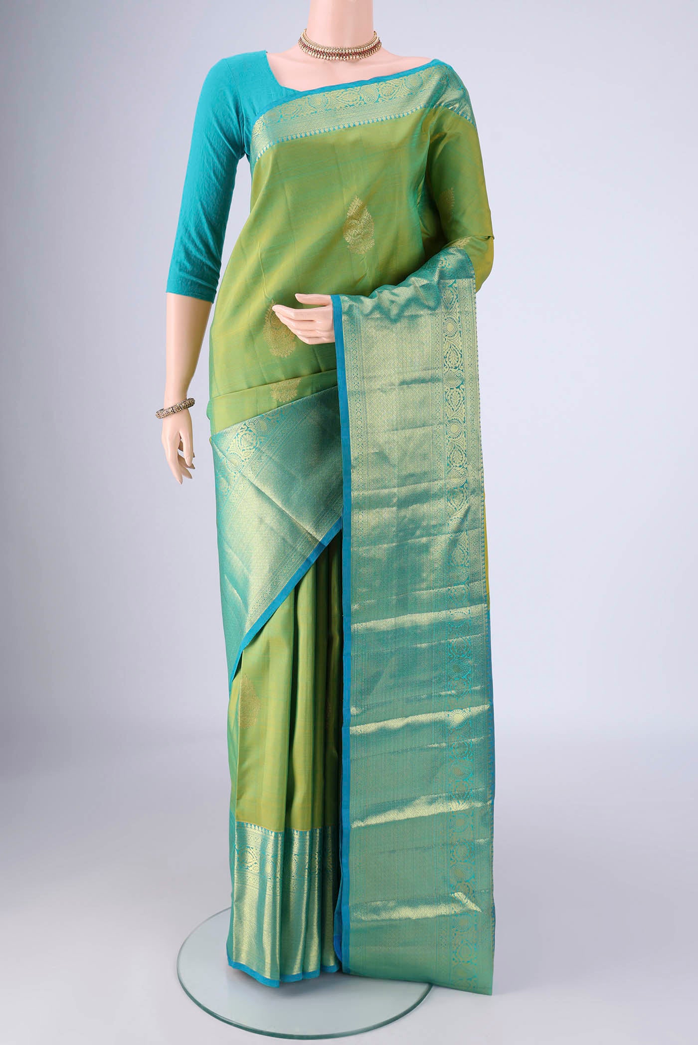 Green Kanchipuram Silk Saree with Zari Butta on the body and Zari Border.  displayed on a mannequin