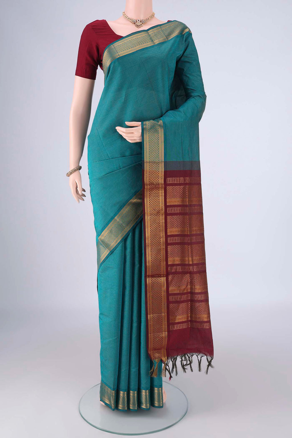 Teal Blended Poly Cotton Saree with Stripes on the body and Zari Border.  displayed on a mannequin