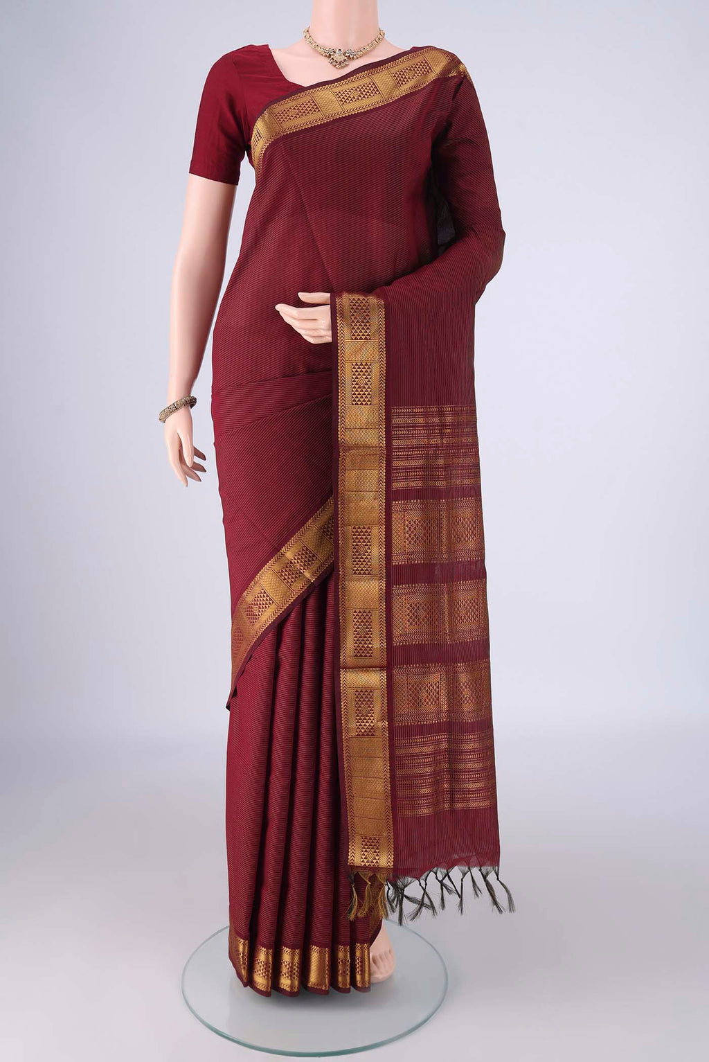 Maroon Blended Poly Cotton Saree with Stripes on the body and Zari Border.  displayed on a mannequin