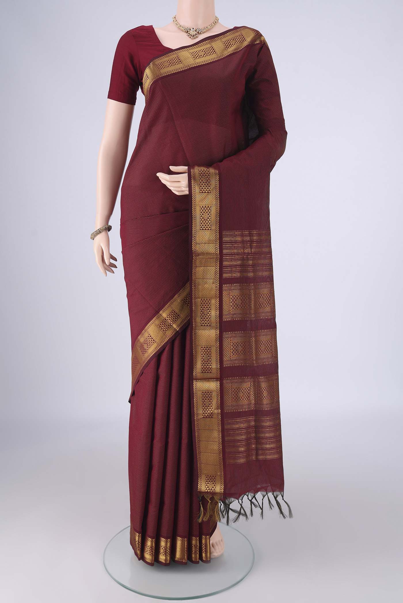 Maroon Blended Poly Cotton Saree with Stripes on the body and Zari Border.  displayed on a mannequin