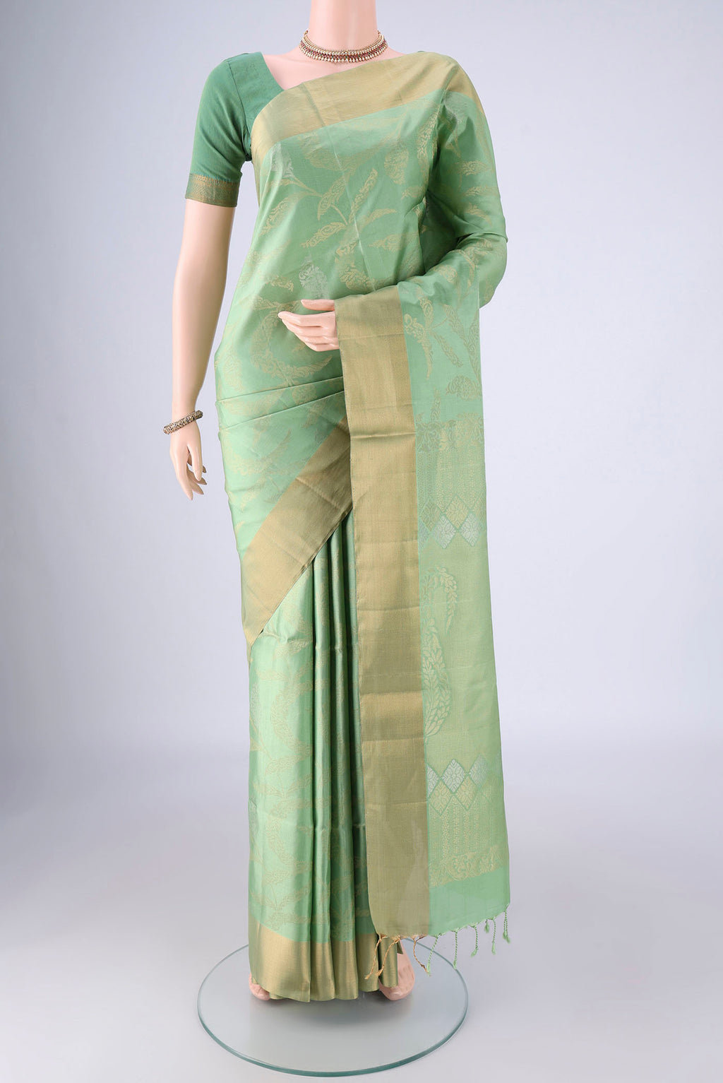 Light Green Soft Silk Saree with Zari Butta on the body and Zari Border.  displayed on a mannequin