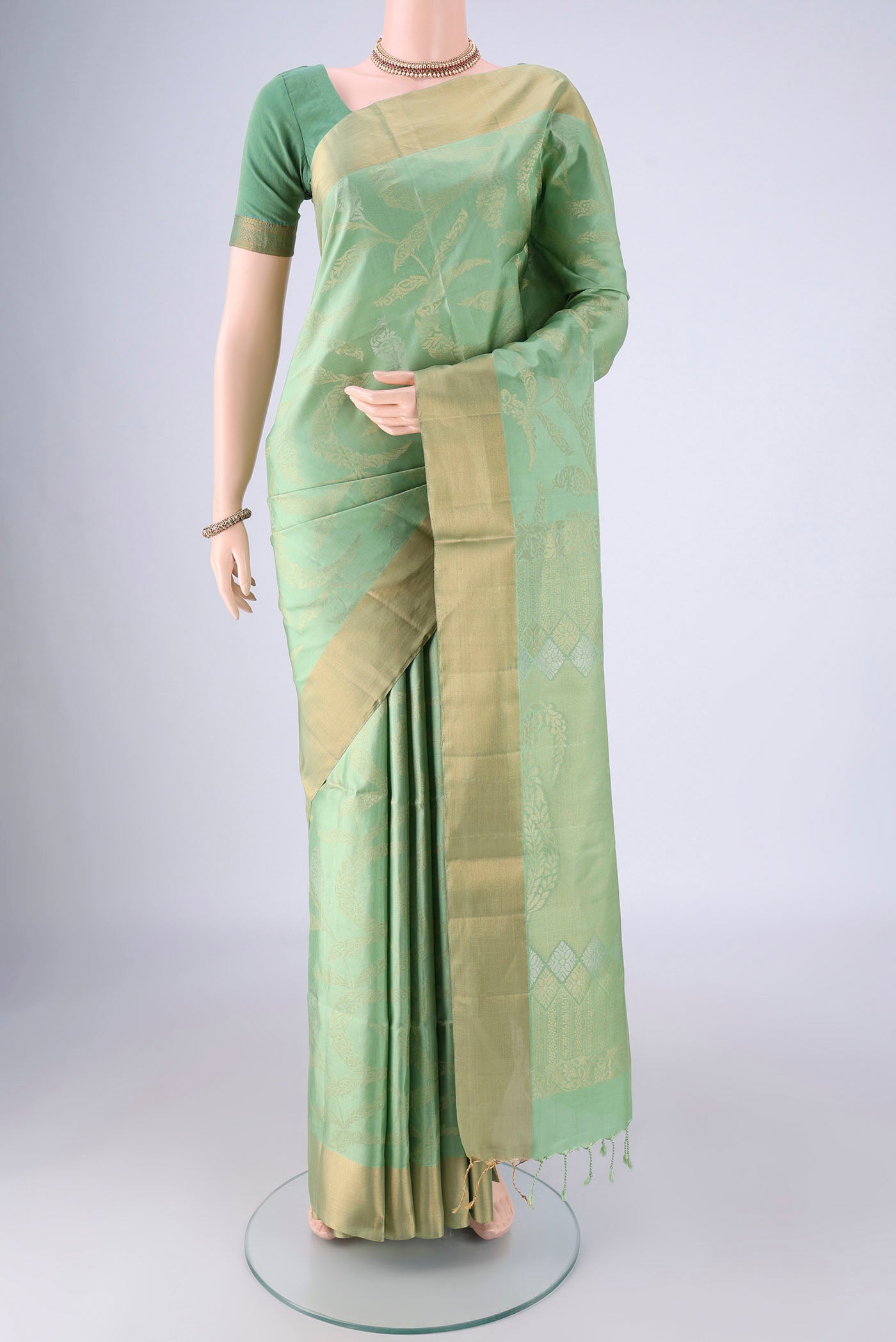 Light Green Soft Silk Saree with Zari Butta on the body and Zari Border.  displayed on a mannequin
