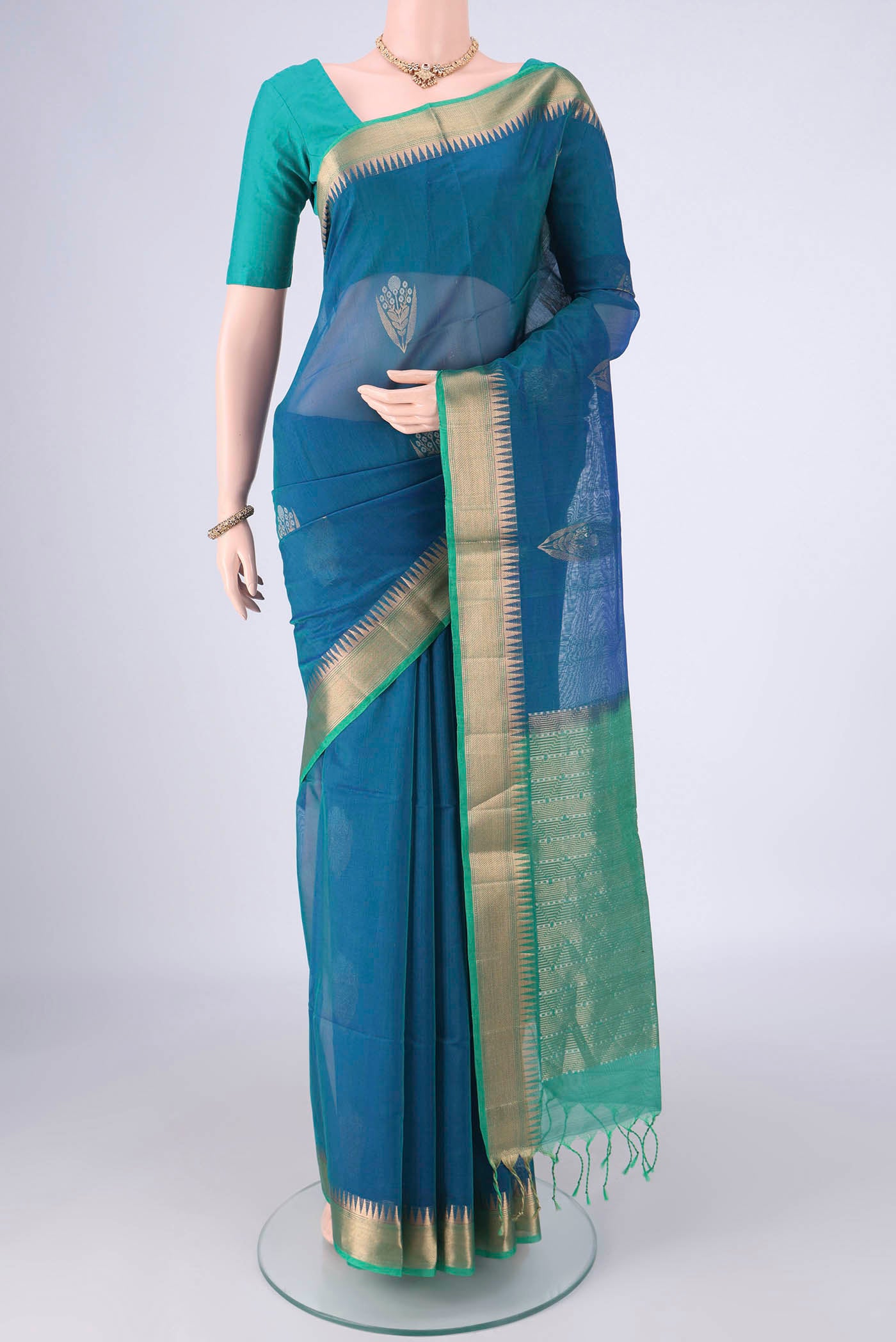 Peacock Blue Kora Cotton Saree with Zari Butta on the body and Zari Border.  displayed on a mannequin