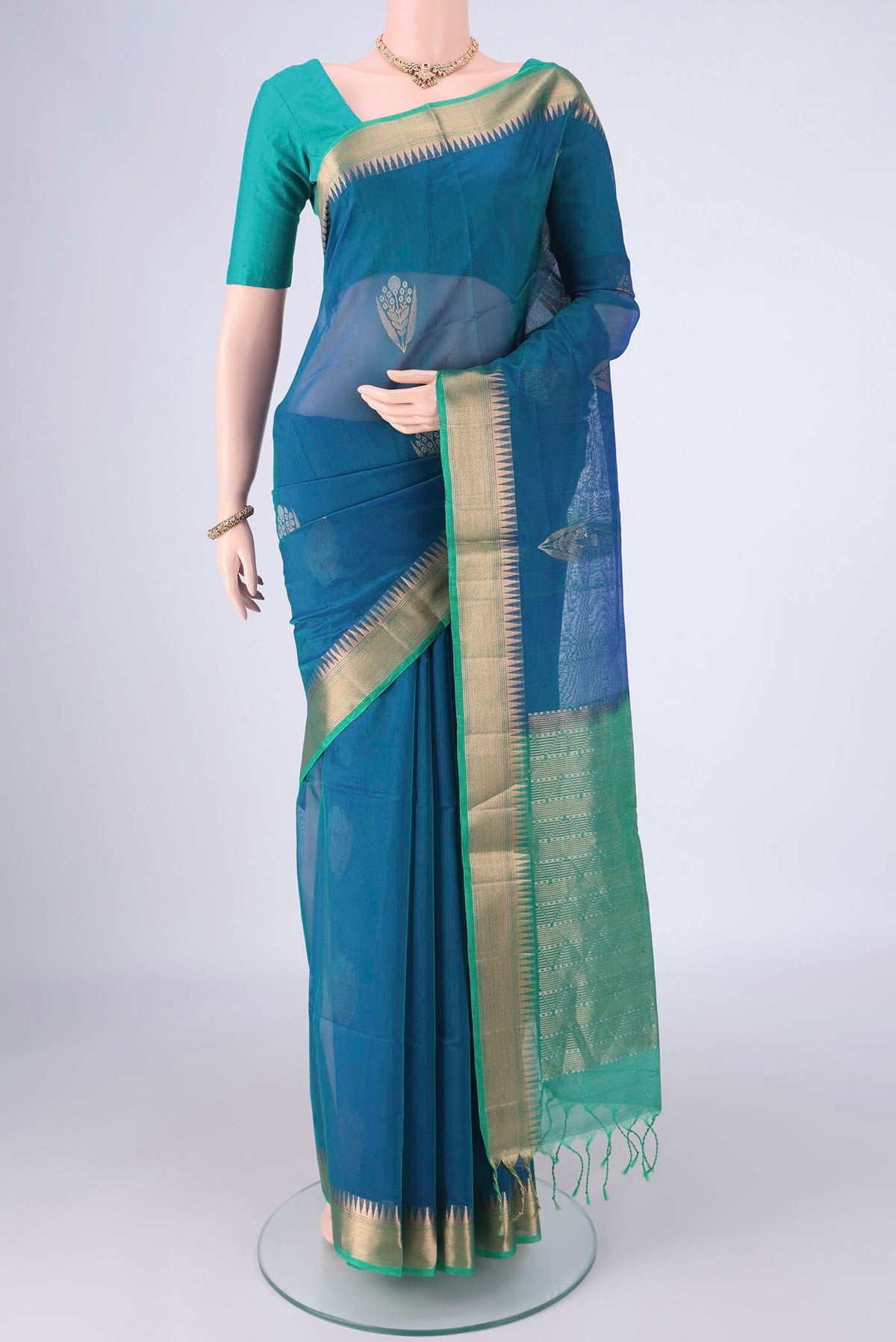 Peacock Blue Kora Cotton Saree with Zari Butta on the body and Zari Border.  displayed on a mannequin