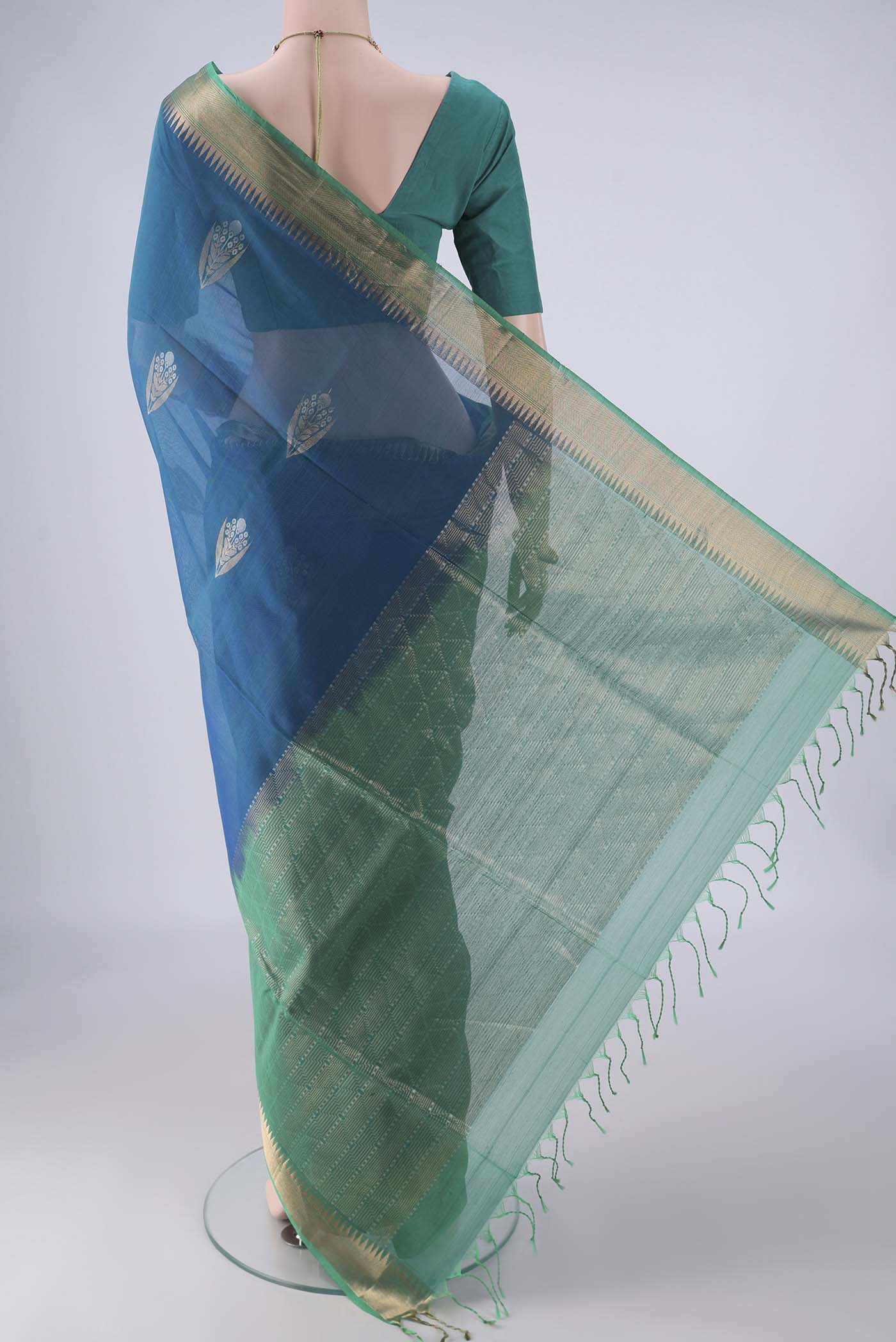 Flat view of Peacock Blue Kora Cotton Saree with Zari Butta on the body and Zari Border. 