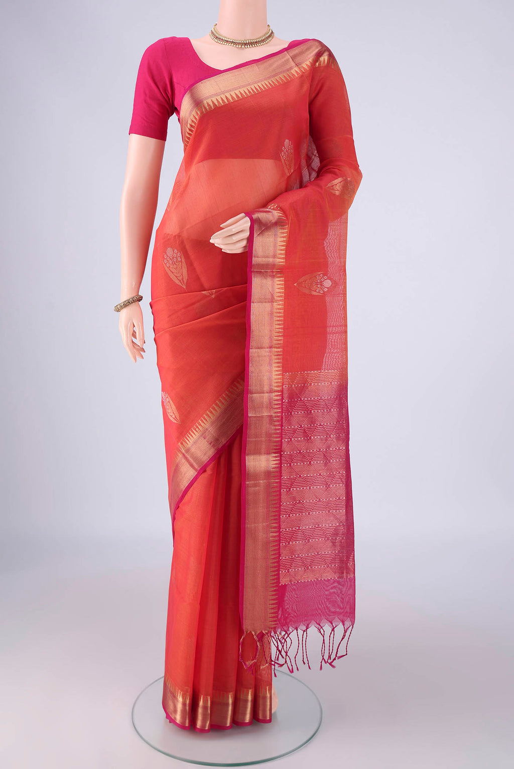 Brick Orange Kora Cotton Saree with Zari Butta on the body and Zari Border.  displayed on a mannequin