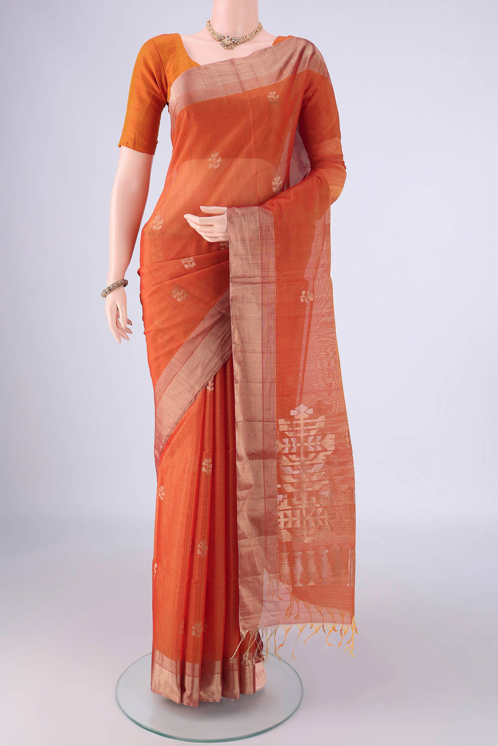 Rust Kora Cotton Saree with Zari Butta on the body and Zari Border.  displayed on a mannequin