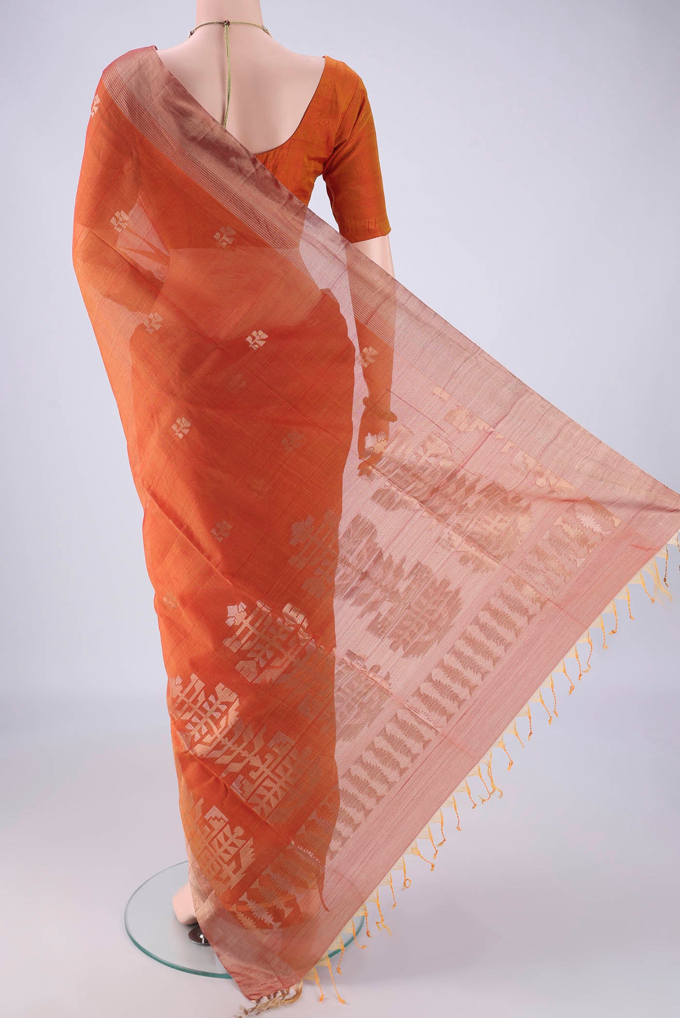 Flat view of Rust Kora Cotton Saree with Zari Butta on the body and Zari Border. 