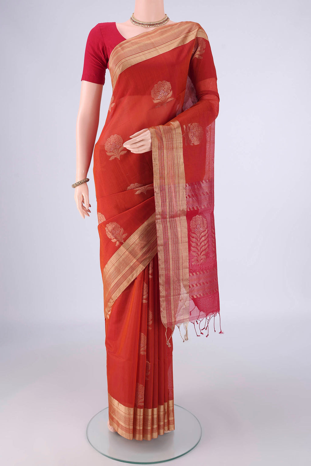 Rust Silk Cotton Saree with Zari Butta on the body and Zari Border.  displayed on a mannequin