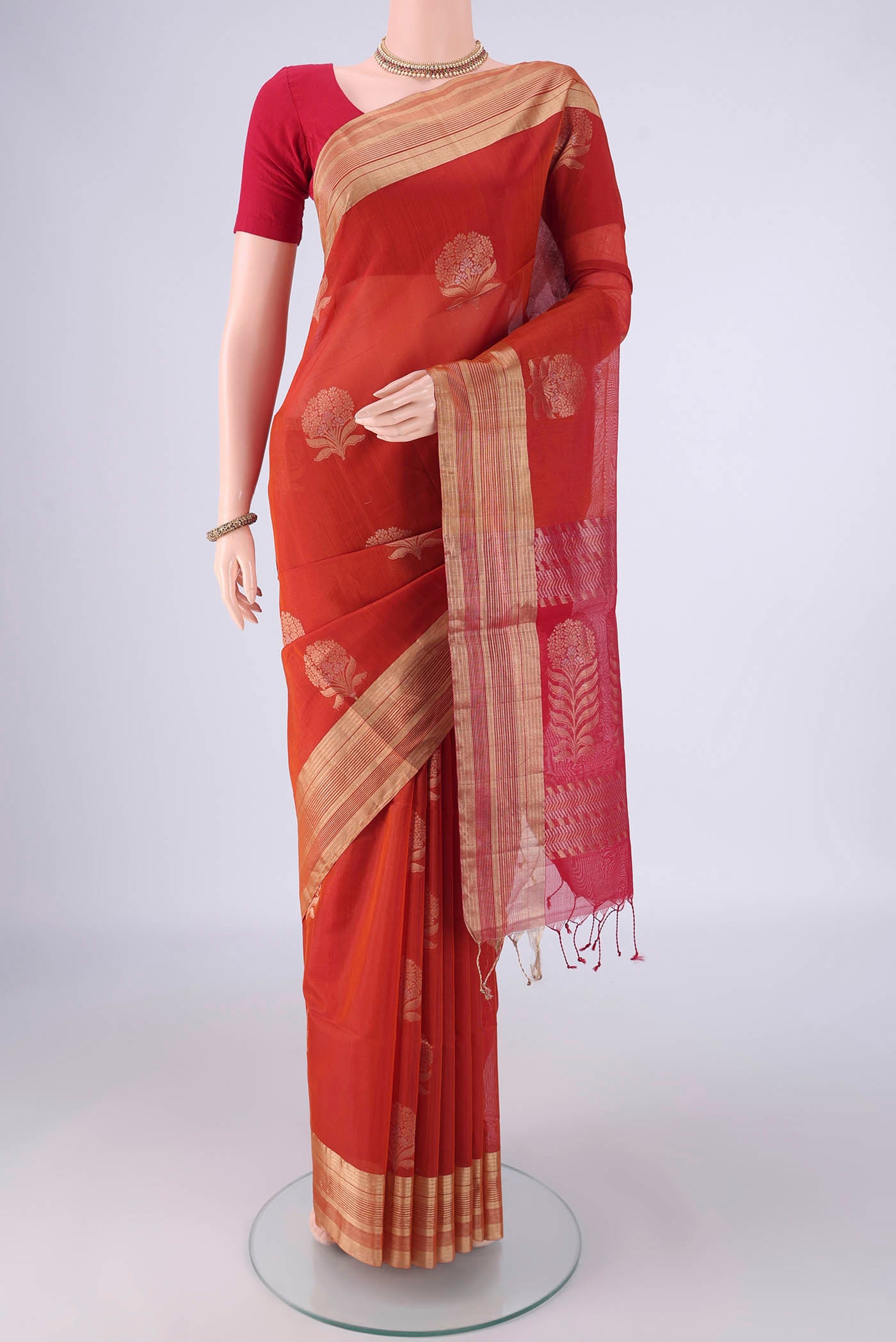 Rust Silk Cotton Saree with Zari Butta on the body and Zari Border.  displayed on a mannequin