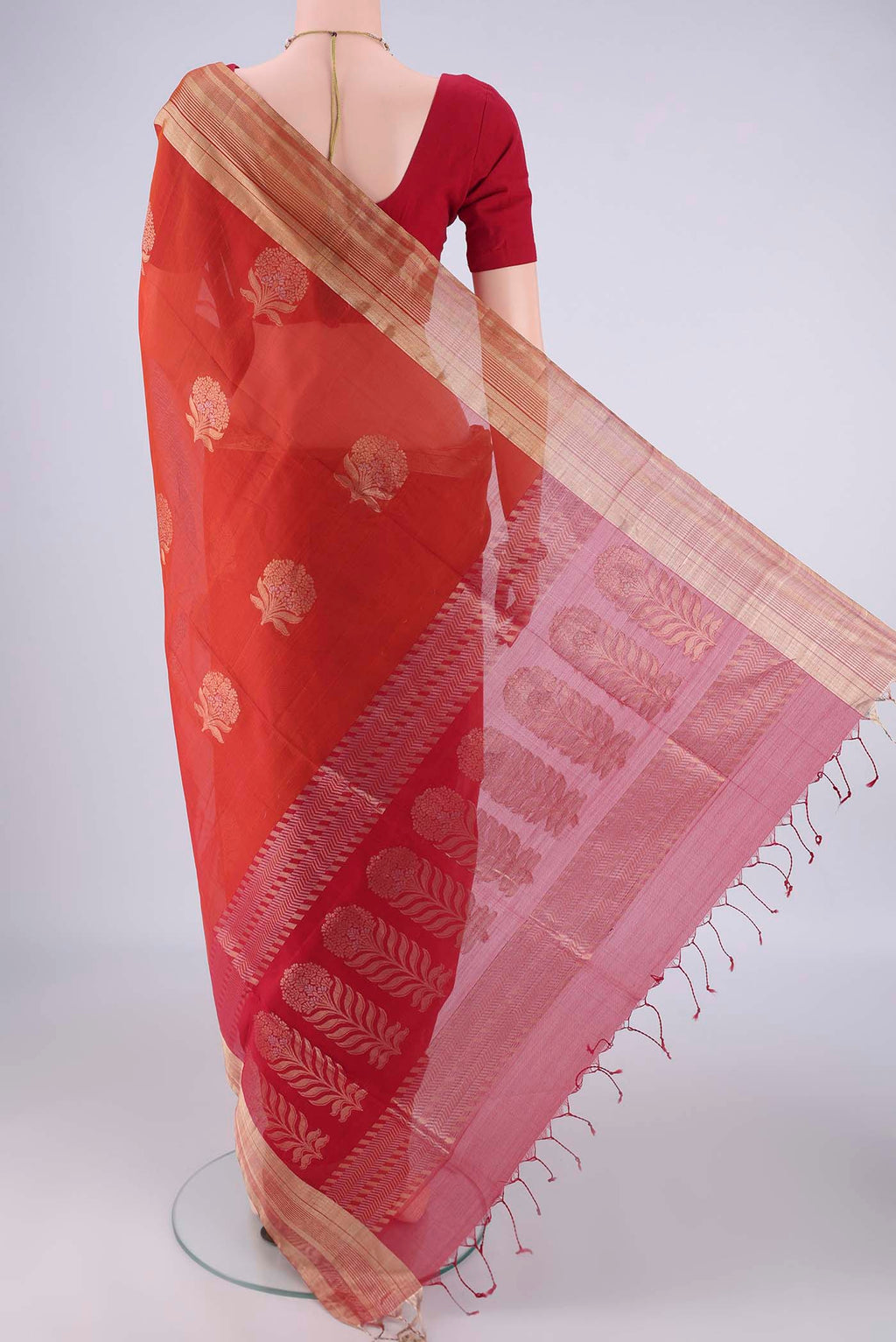 Flat view of Rust Silk Cotton Saree with Zari Butta on the body and Zari Border. 