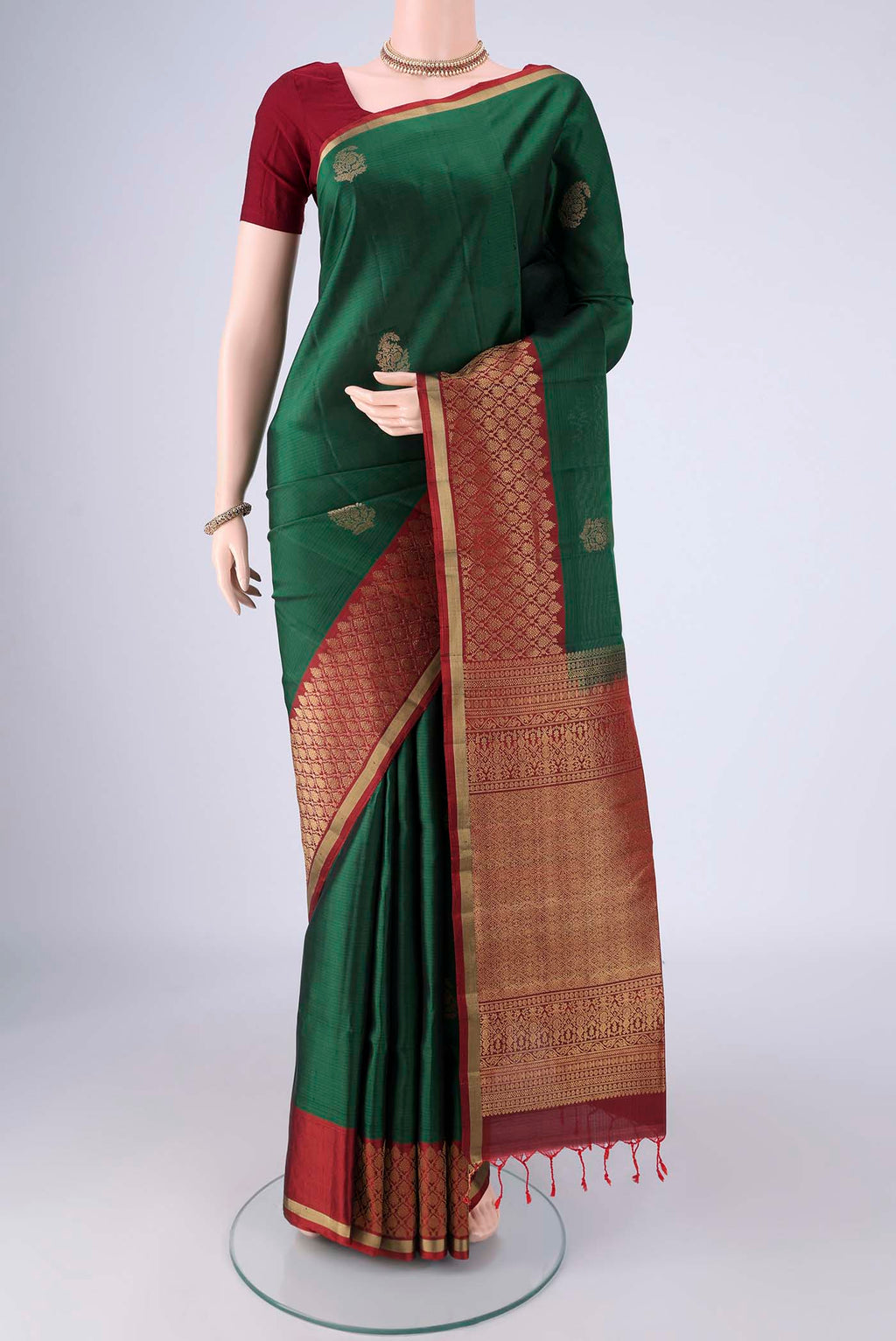 Bottle Green Soft Silk Saree with Zari Butta on the body and Zari Border.  displayed on a mannequin