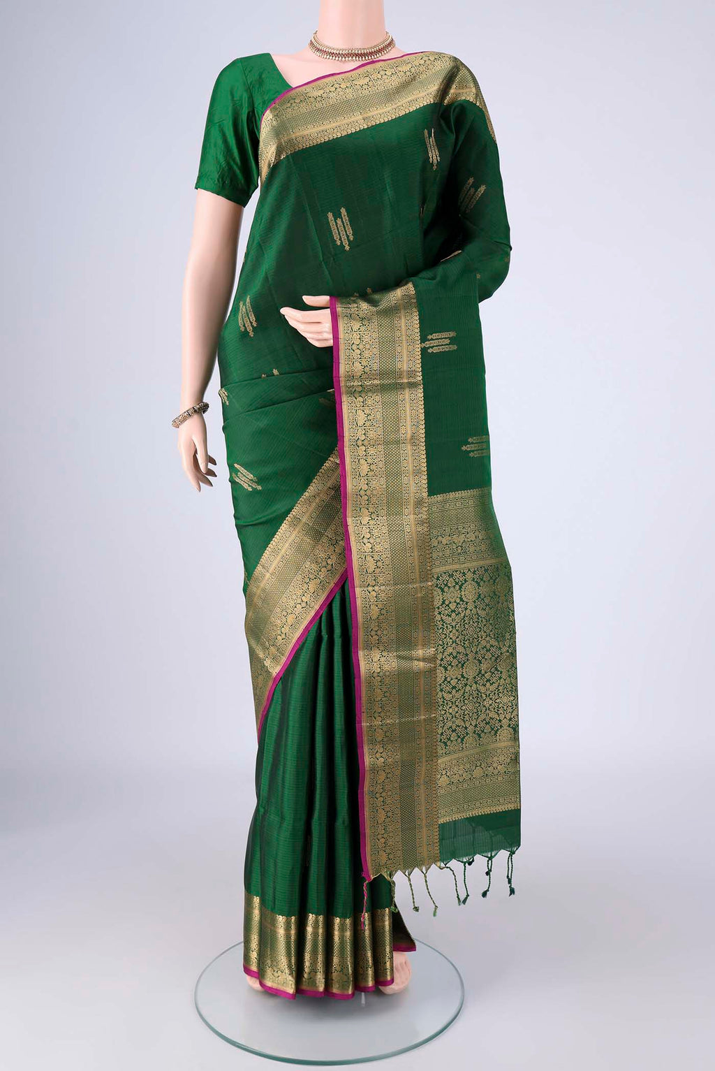 Bottle Green Soft Silk Saree with Zari Butta on the body and Zari Border.  displayed on a mannequin