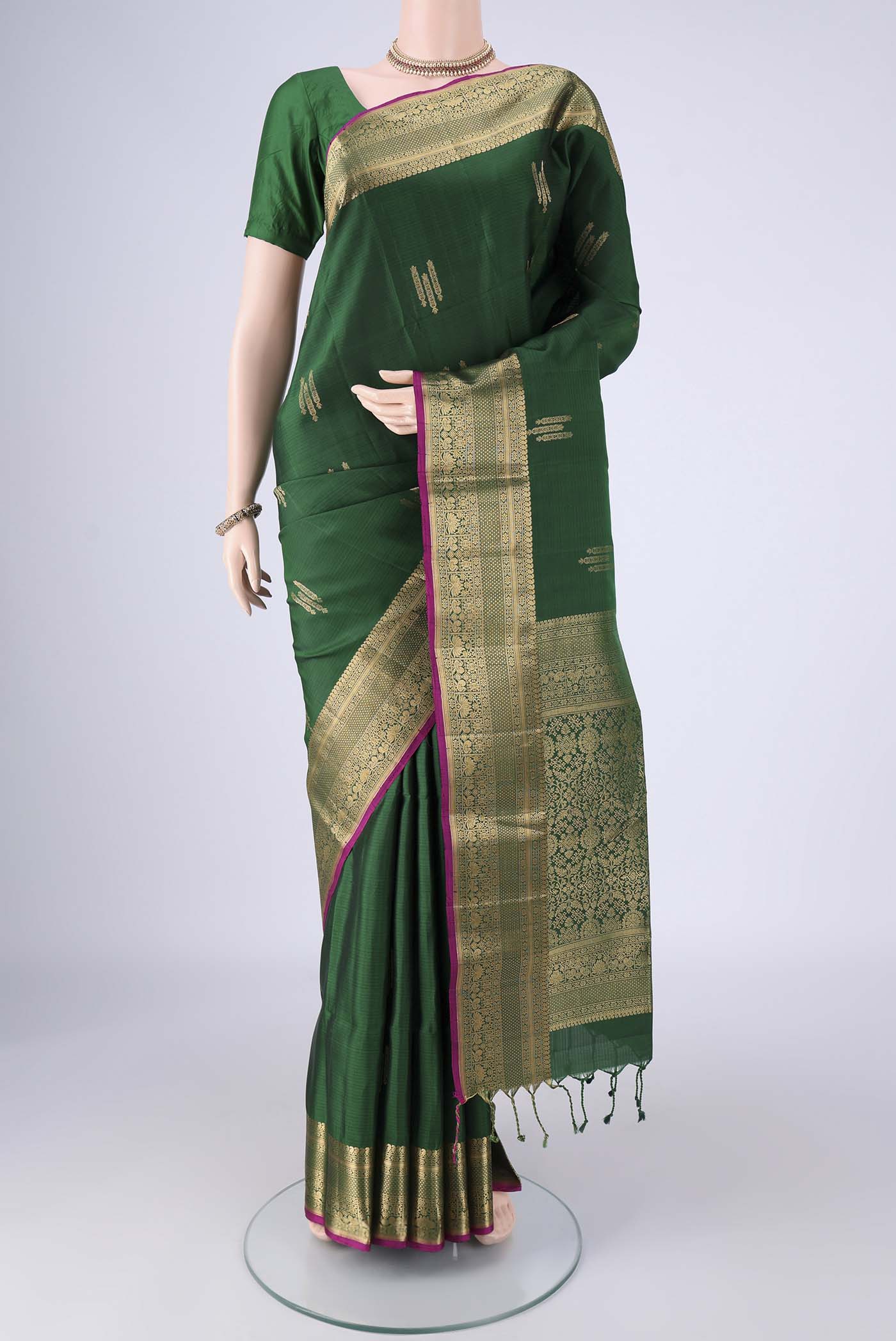 Bottle Green Soft Silk Saree with Zari Butta on the body and Zari Border.  displayed on a mannequin