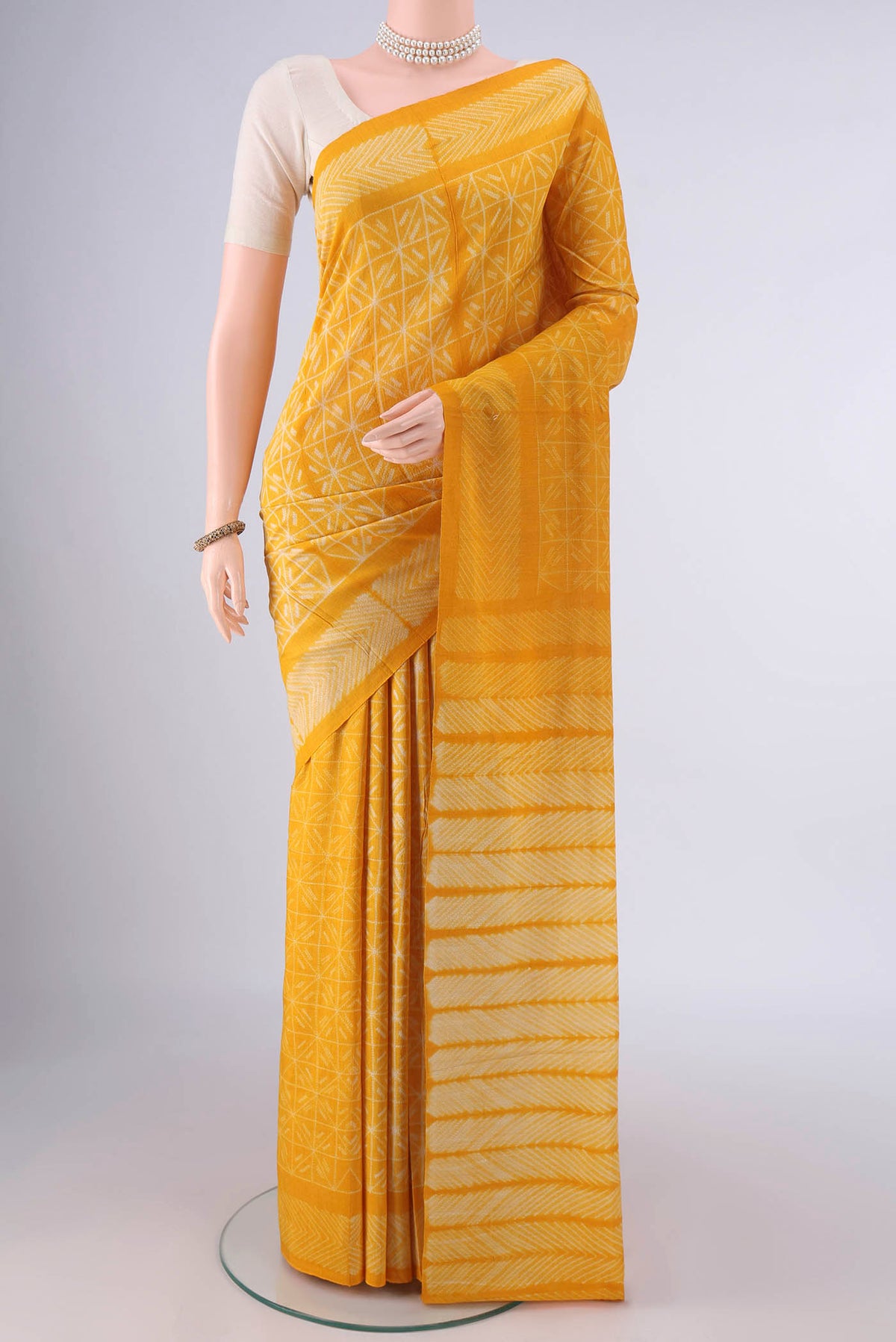 Yellow Tussar Saree with Printed design on the body and Printed Border.  displayed on a mannequin