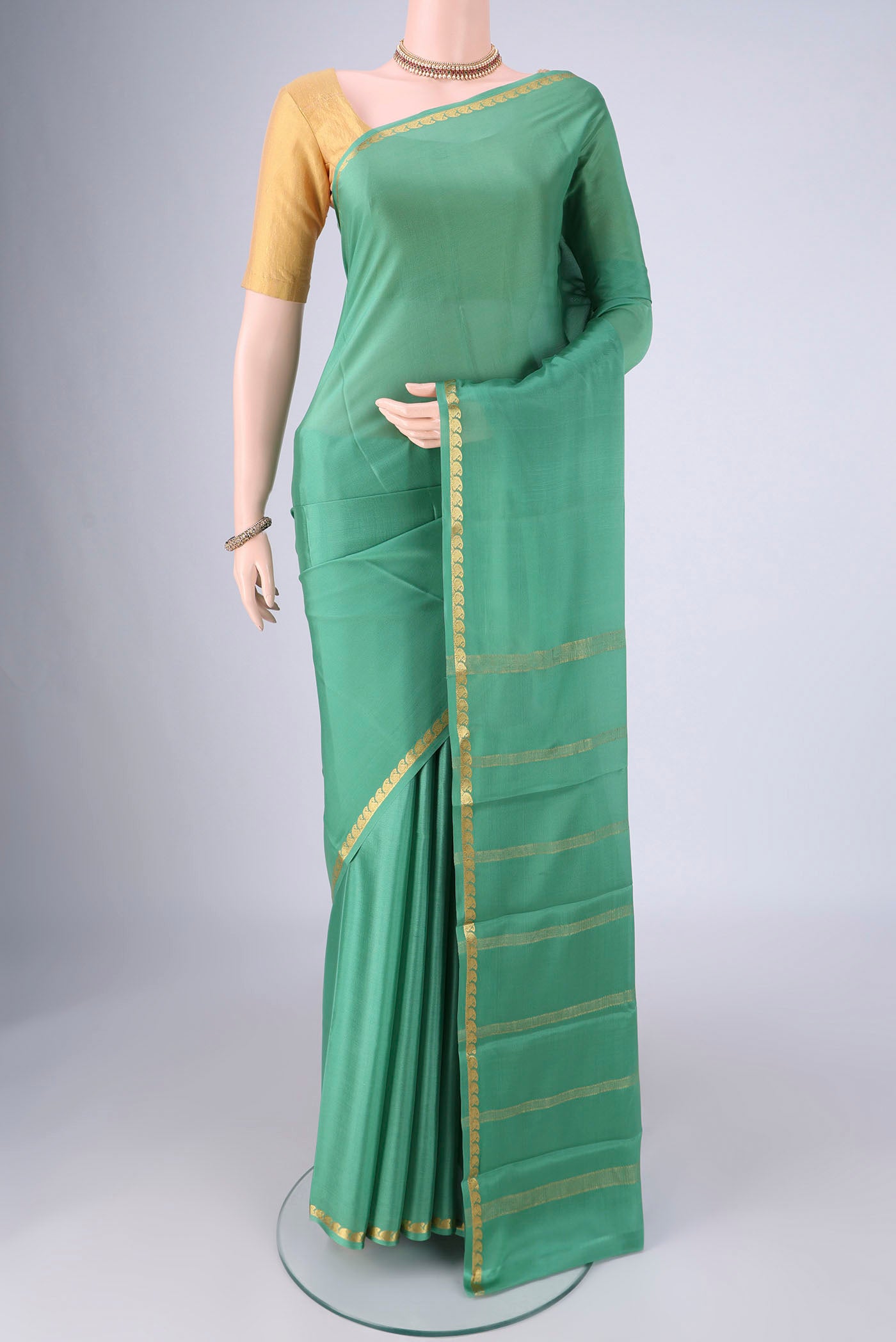 Light Green Mysore Crepe Saree with Plain Body and Zari Border.  displayed on a mannequin