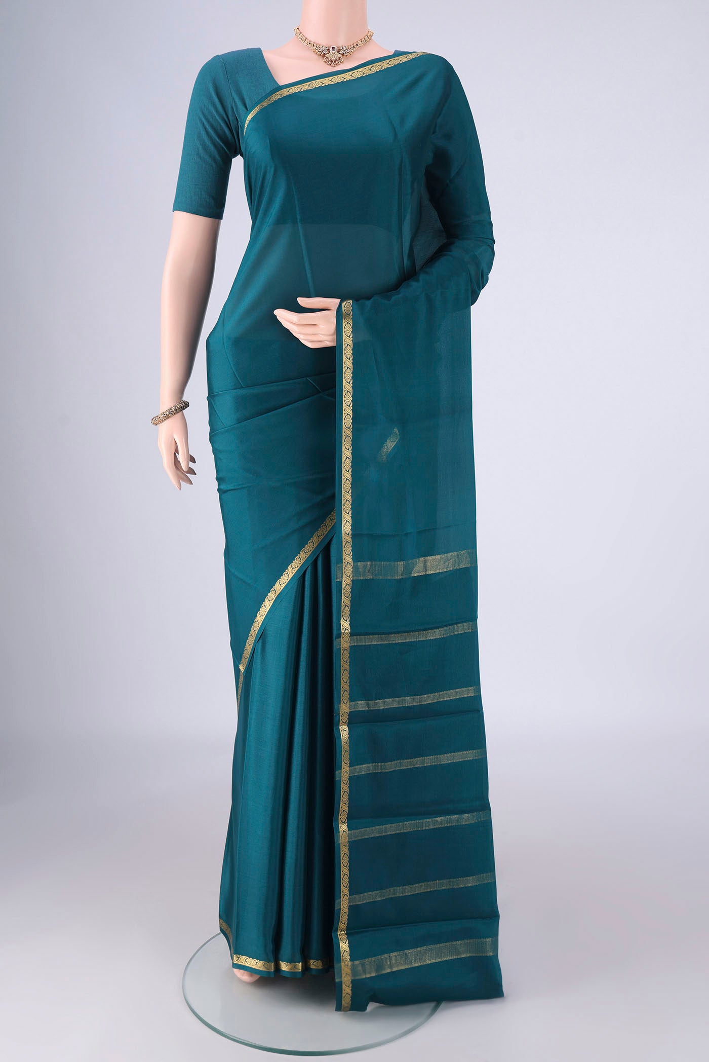 Teal Mysore Crepe Saree with Plain Body and Zari Border.  displayed on a mannequin