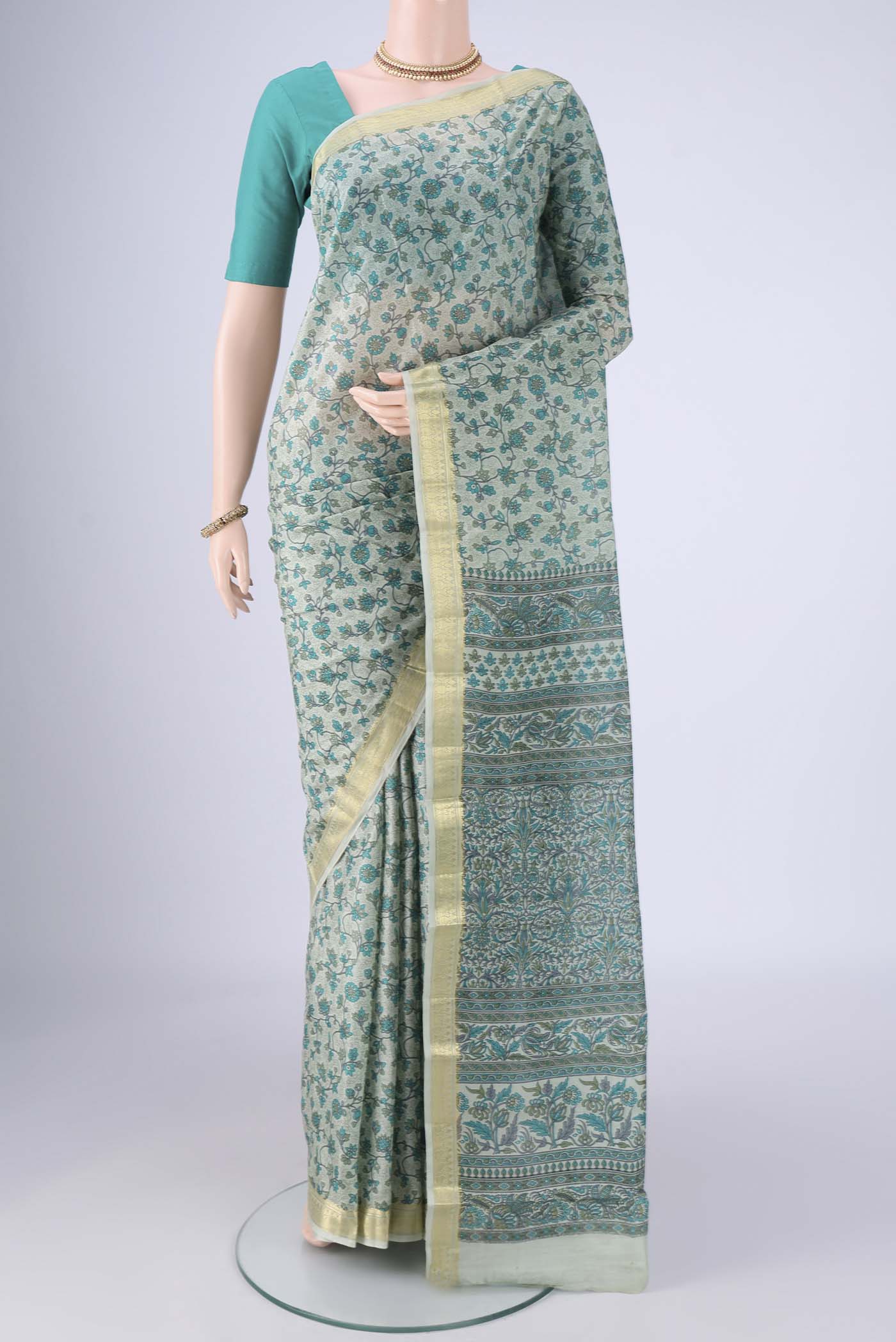 Sage Green Printed Silk Saree with Printed design on the body and Zari Border.  displayed on a mannequin