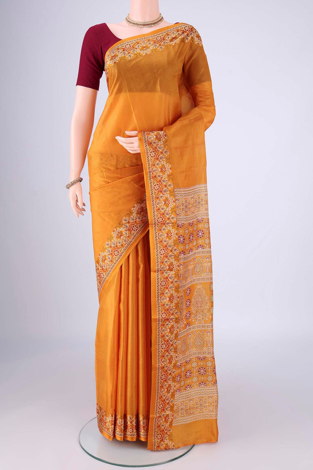 Mustard Printed Silk Saree with Plain Body and Printed Border.  displayed on a mannequin