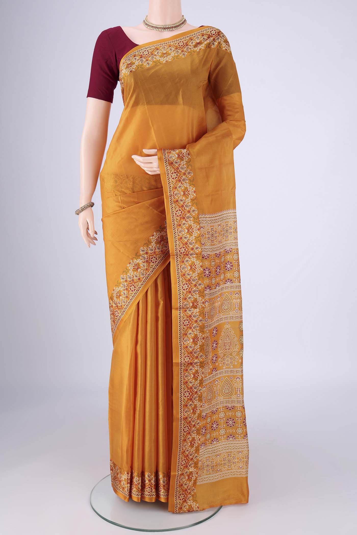 Mustard Printed Silk Saree with Plain Body and Printed Border.  displayed on a mannequin