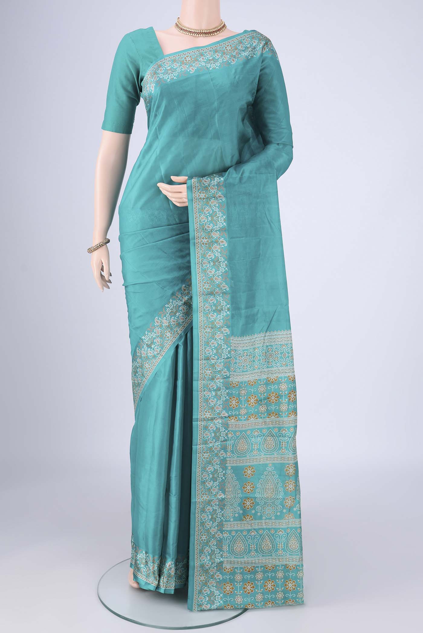 Turquoise Printed Silk Saree with Plain Body and Printed Border.  displayed on a mannequin