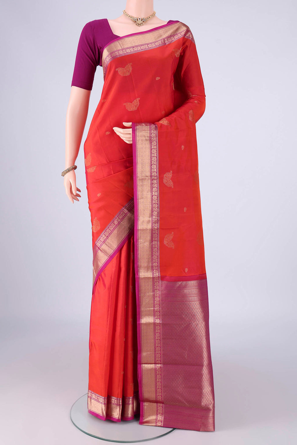 Orange Kanchipuram Silk Saree with Zari Butta on the body and Zari Border.  displayed on a mannequin
