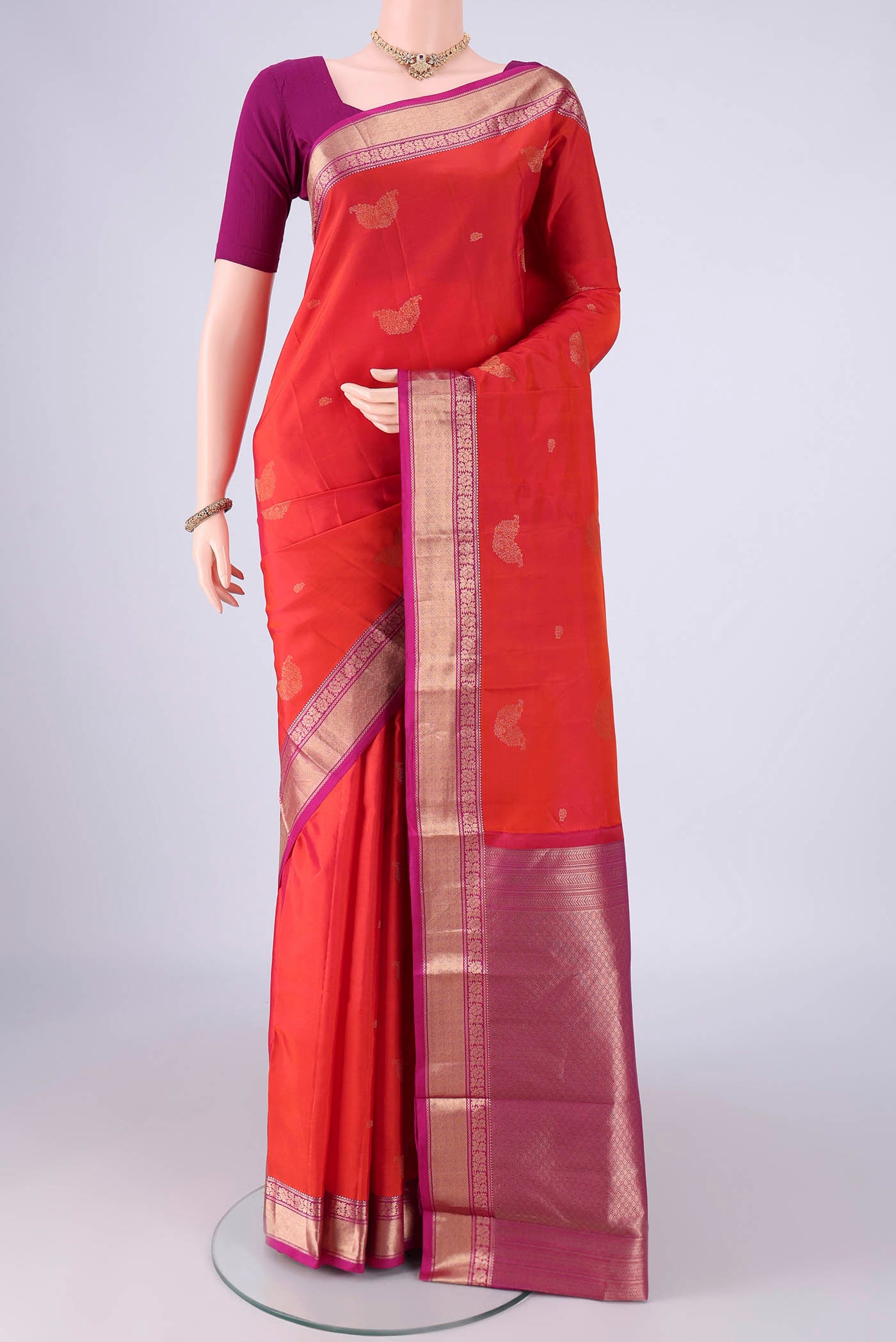 Orange Kanchipuram Silk Saree with Zari Butta on the body and Zari Border.  displayed on a mannequin