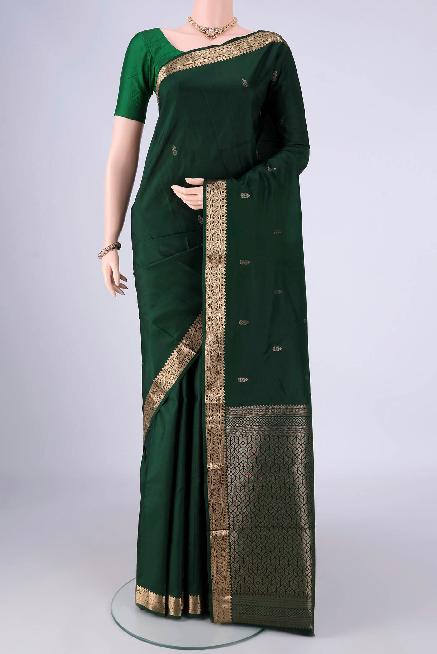 Bottle Green Kanjivaram Silk Saree with Zari Butta on the body and Zari Border.  displayed on a mannequin