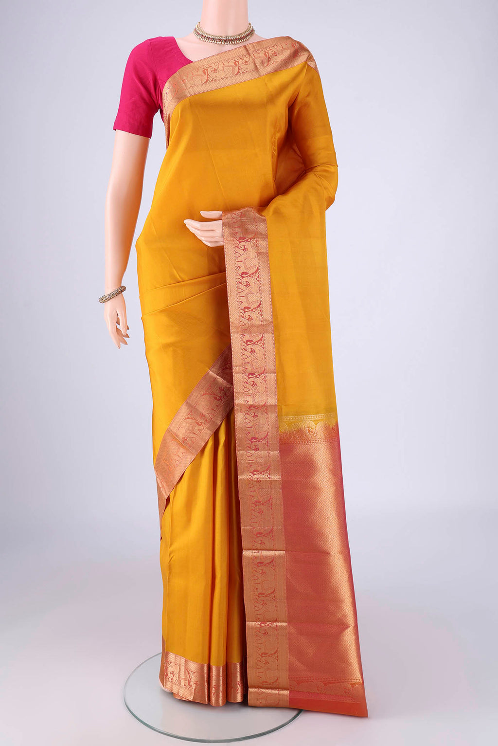 Mustard Kanjivaram Silk Saree with Plain Body and Zari Border.  displayed on a mannequin