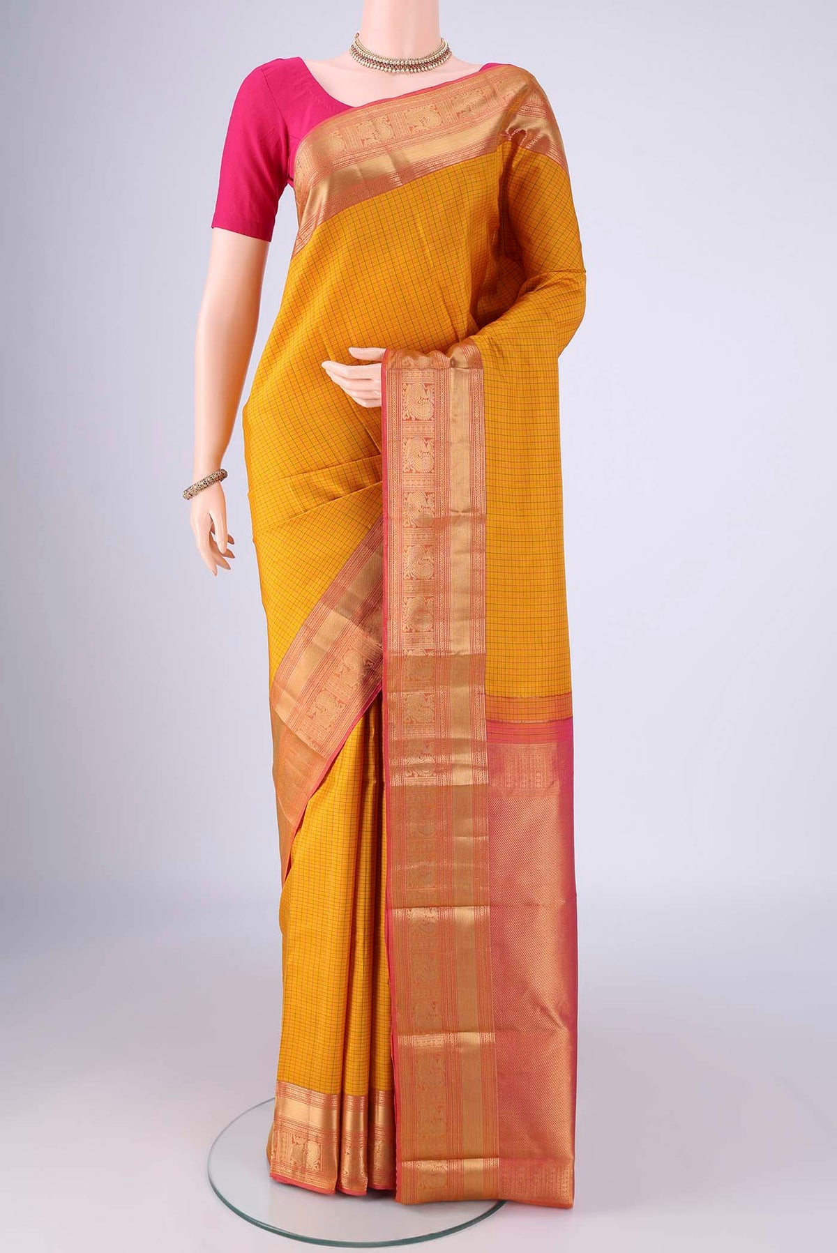 Mustard Kanchipuram Silk Saree with Checked design on the body and Zari Border.  displayed on a mannequin
