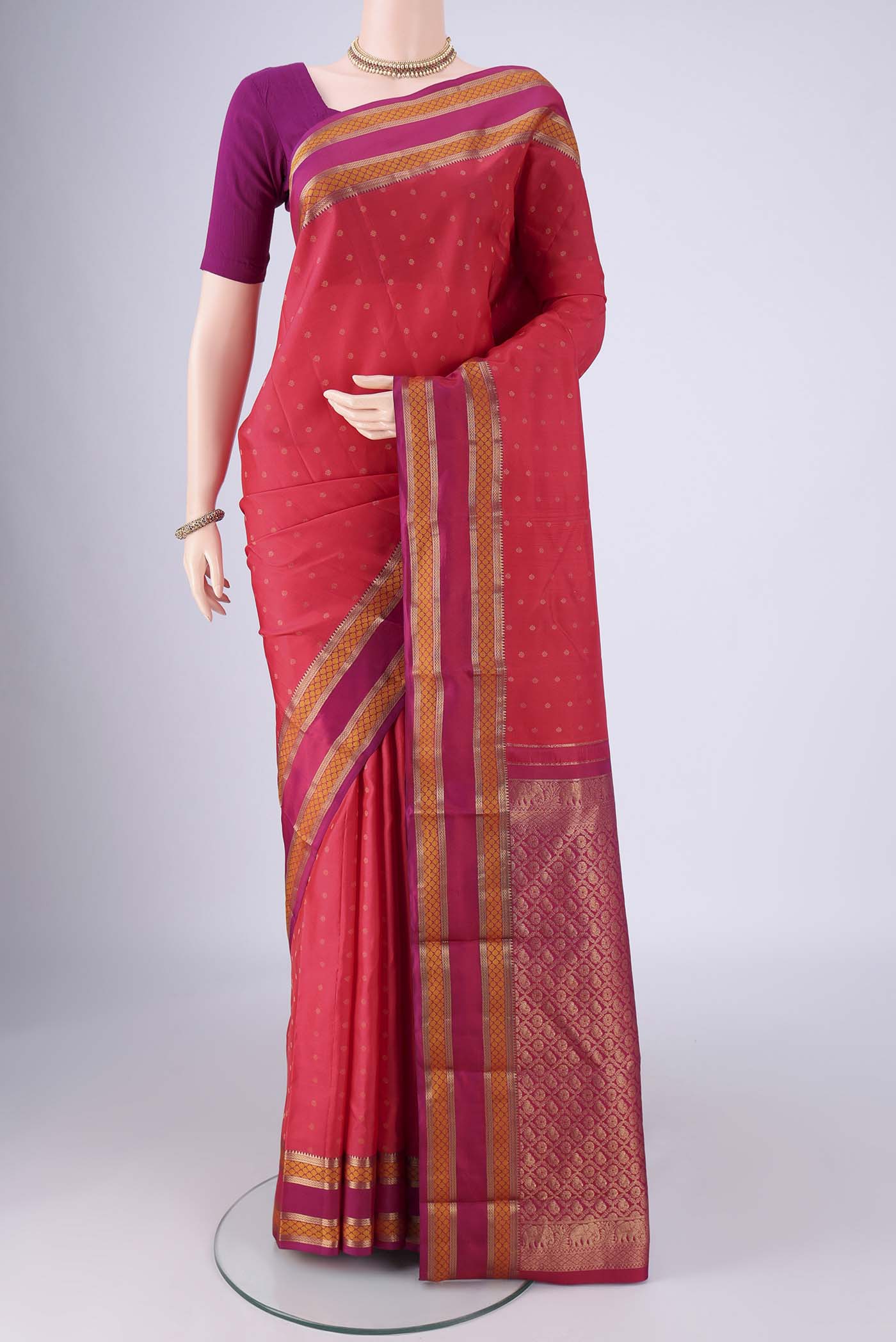 Coral Kanchipuram Silk Saree with Zari Butta on the body and Zari And Thread Border.  displayed on a mannequin
