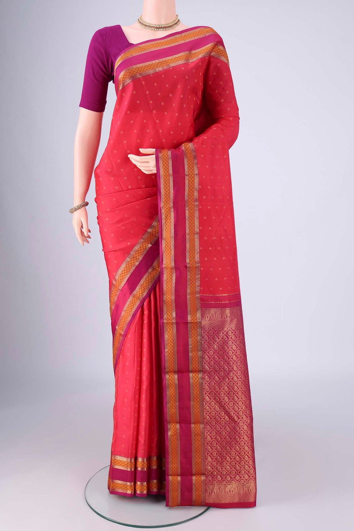 Coral Kanchipuram Silk Saree with Zari Butta on the body and Zari And Thread Border.  displayed on a mannequin