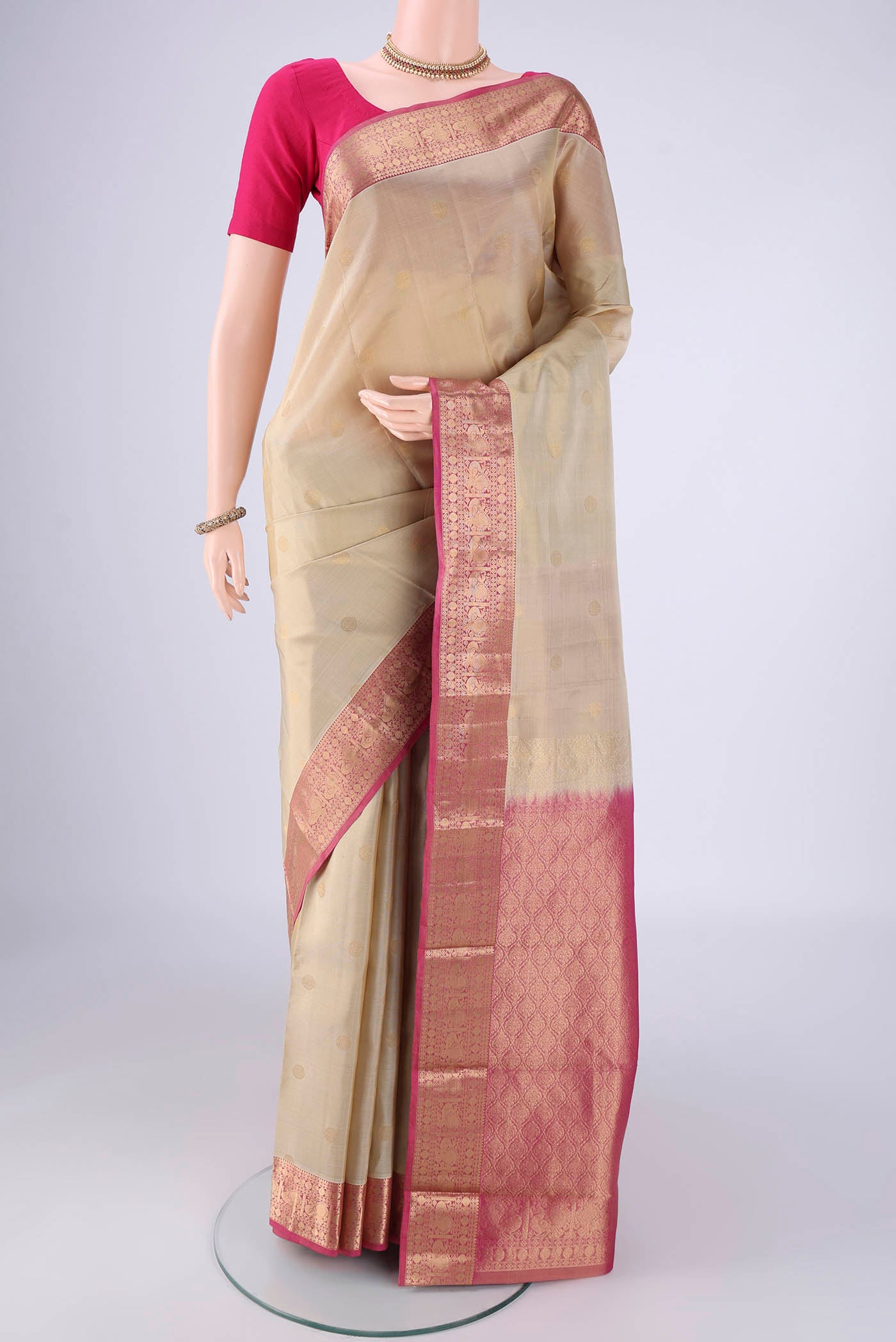 Beige Kanchipuram Silk Saree with Zari Butta on the body and Zari Border.  displayed on a mannequin