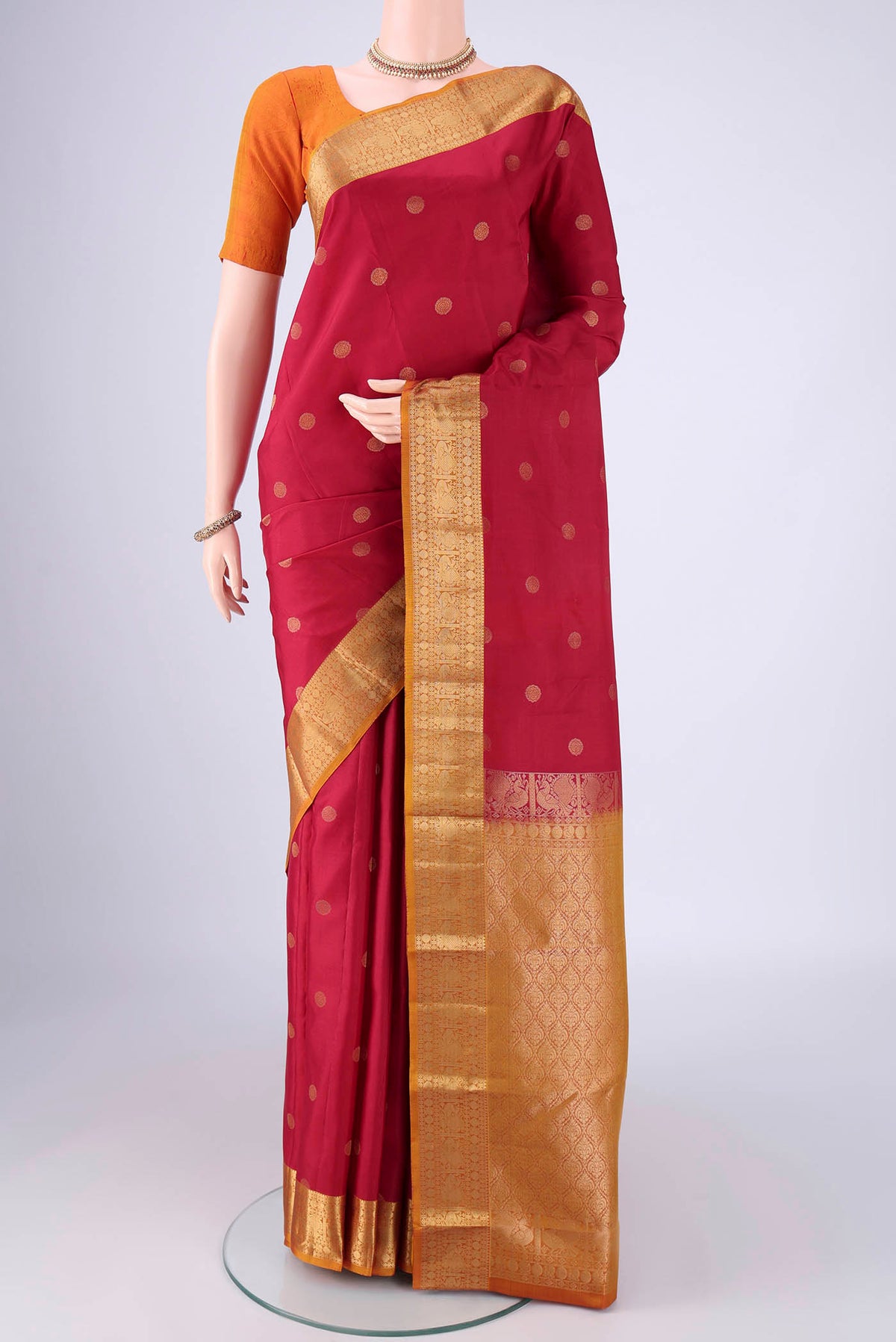 Maroon Kanchipuram Silk Saree with Zari Butta on the body and Zari Border.  displayed on a mannequin