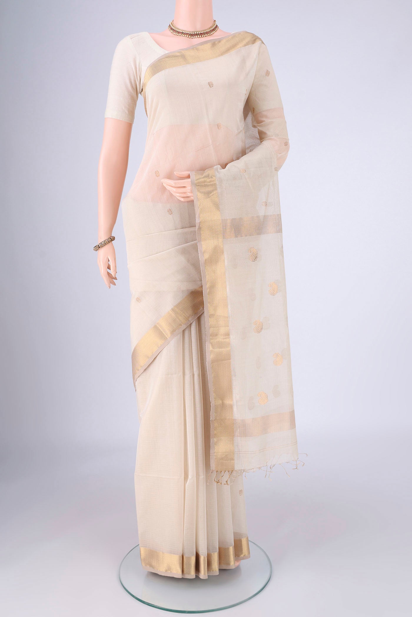 Cream Maheshwari Silk Cotton Saree with Zari Butta on the body and Zari Border.  displayed on a mannequin