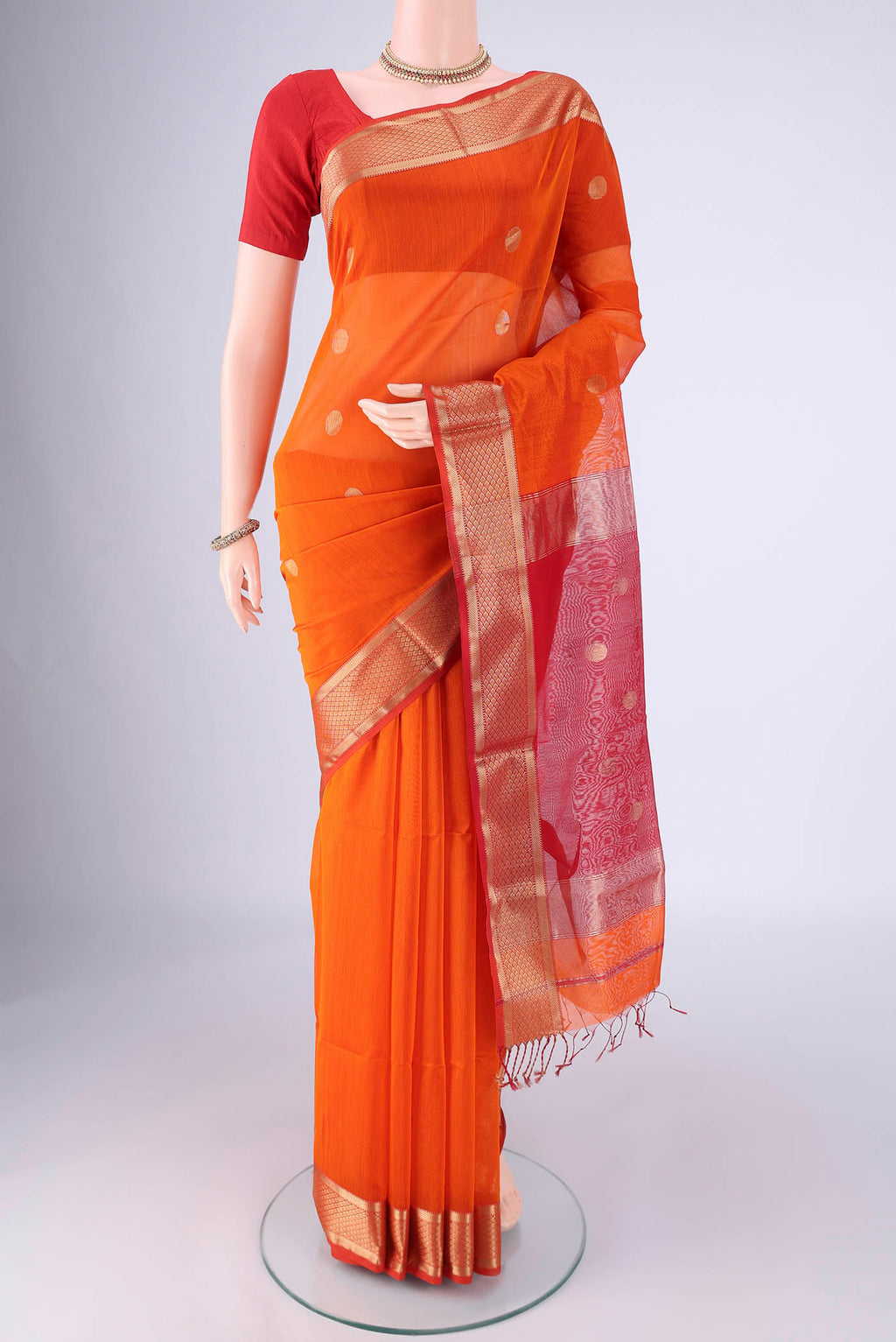 Brick Orange Maheshwari Silk Cotton Saree with Zari Butta on the body and Zari Border.  displayed on a mannequin