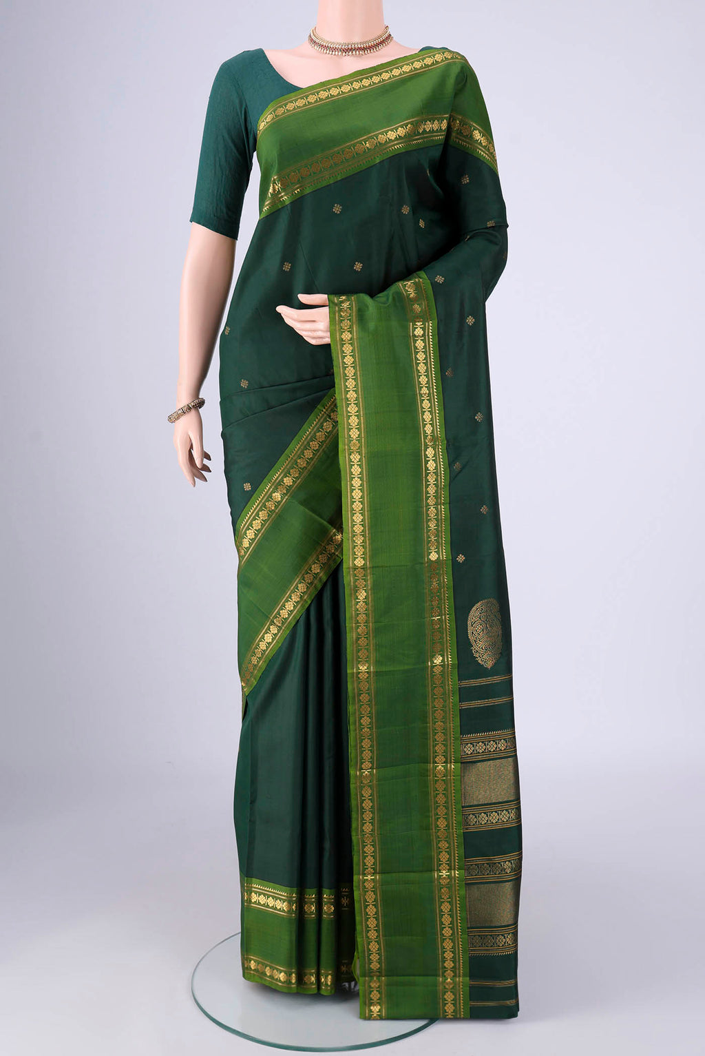Bottle Green Kanchipuram Silk Saree with Zari Butta on the body and Zari Border.  displayed on a mannequin