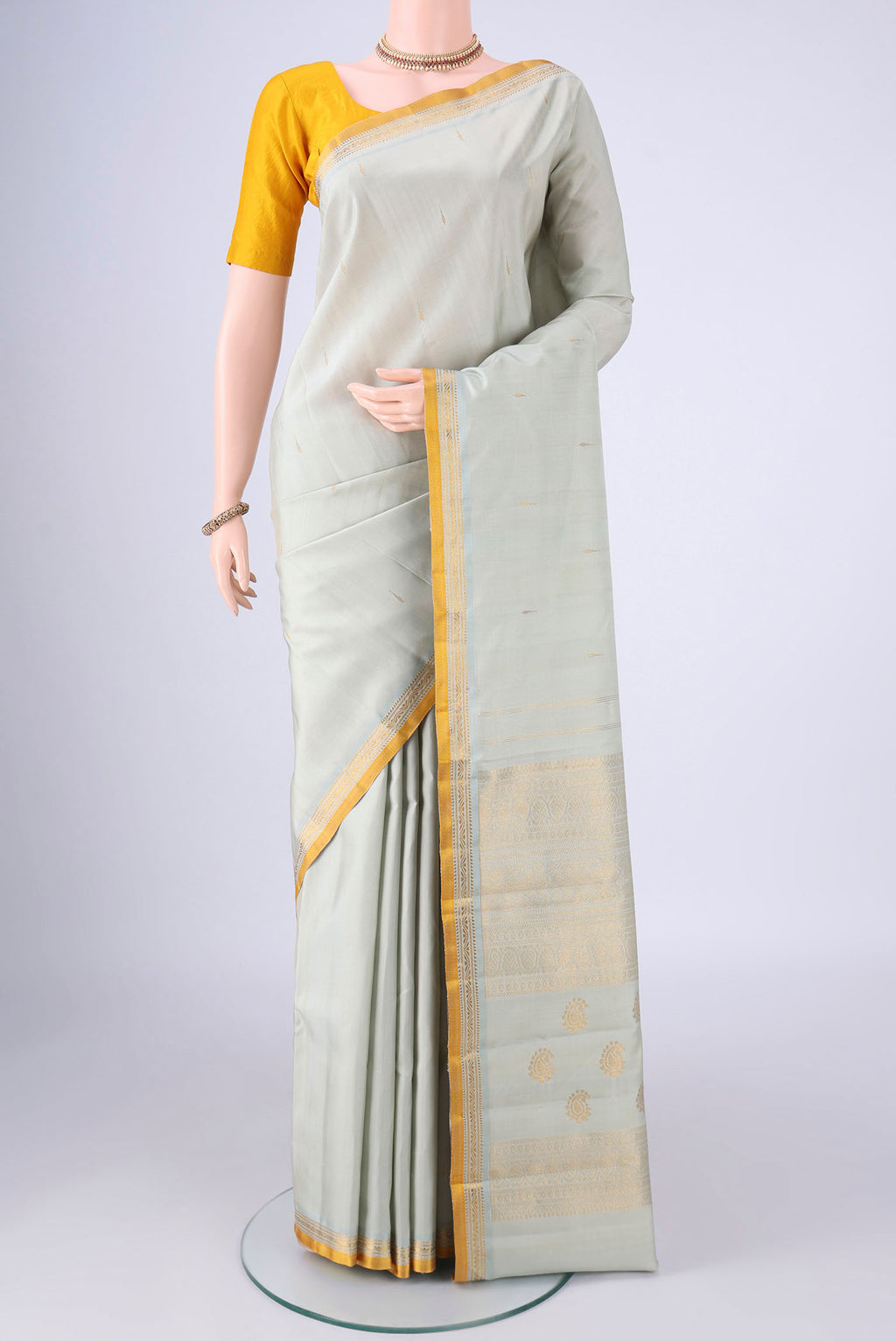 Light Green Kanjivaram Silk Saree with Zari Butta on the body and Zari Border.  displayed on a mannequin