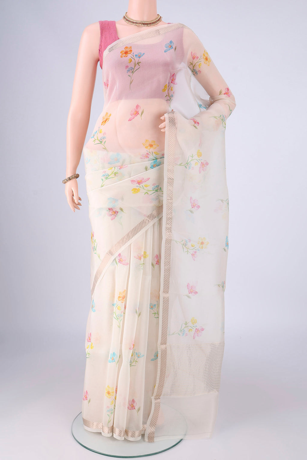Off White Organza Silk Saree with Floral Print on the body and Zari Border.  displayed on a mannequin