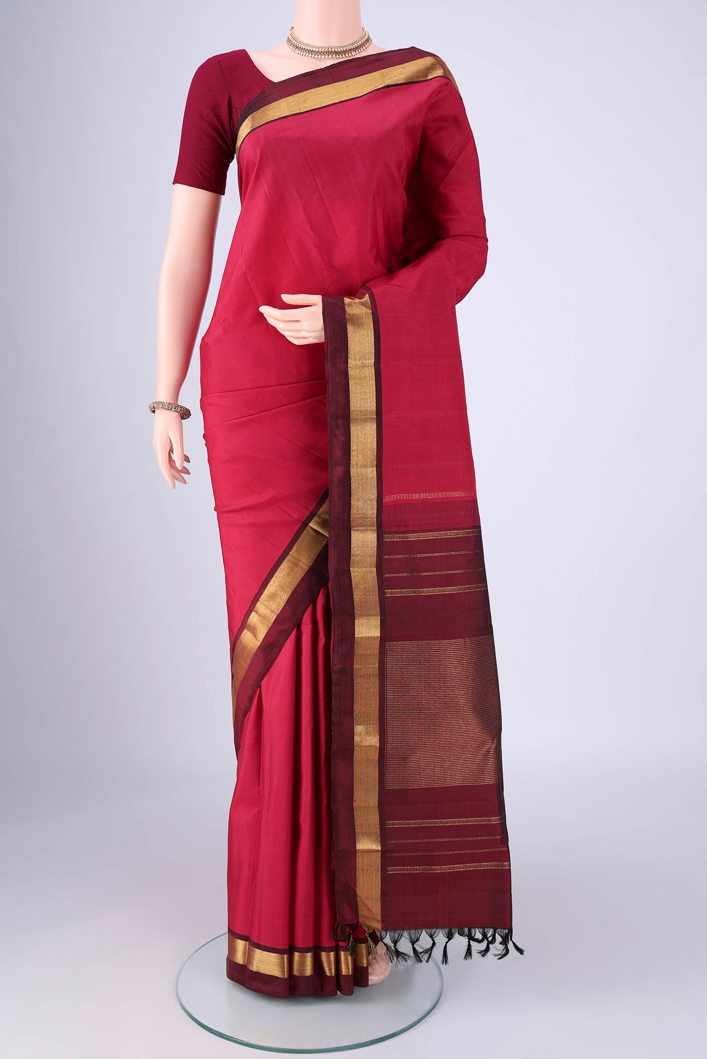 Coral Kanjivaram Silk Saree with Plain Body and Zari Border.  displayed on a mannequin