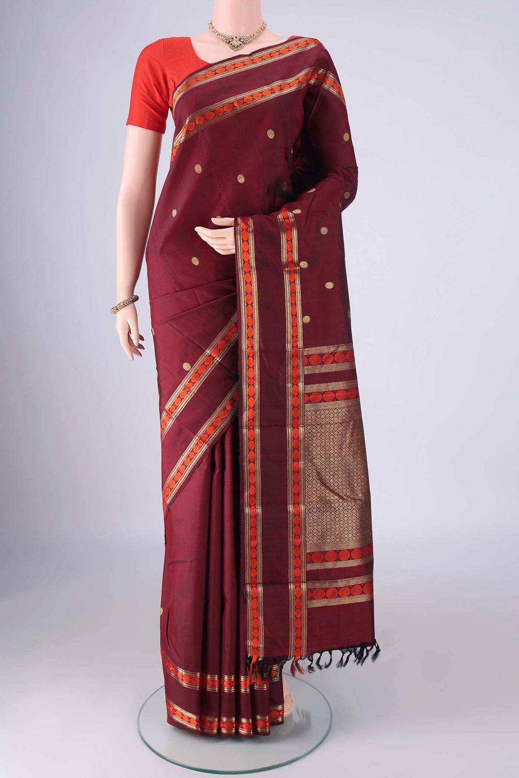 Maroon Kanjivaram Silk Saree with Zari Butta on the body and Zari And Thread Border.  displayed on a mannequin