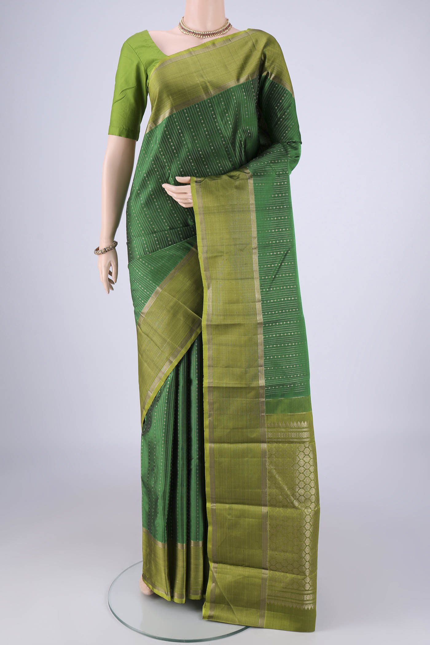 Bottle Green Kanchipuram Silk Saree with Stripes on the body and Zari Border.  displayed on a mannequin